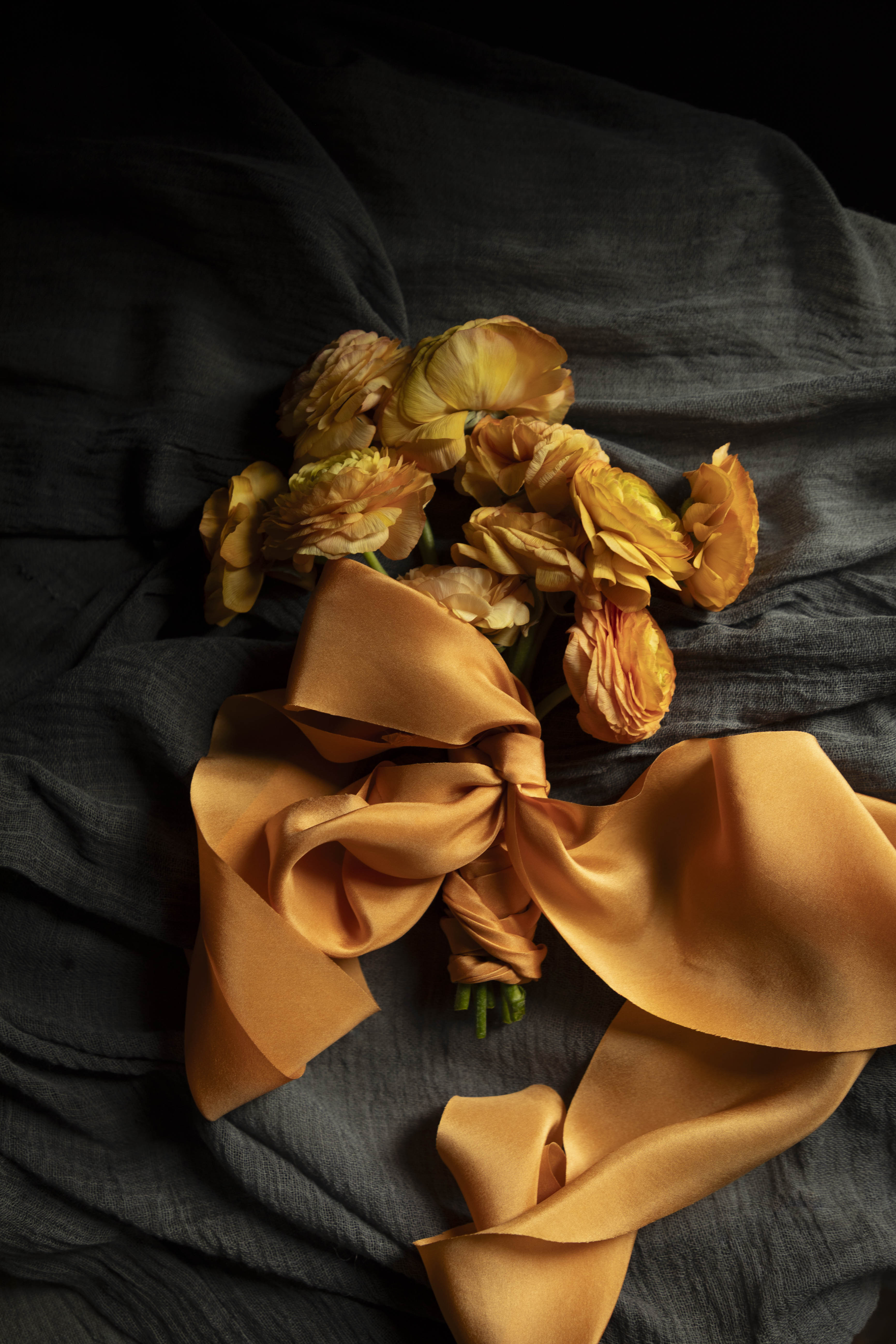 Orange ranunculus flower arrangement with orange silk ribbon