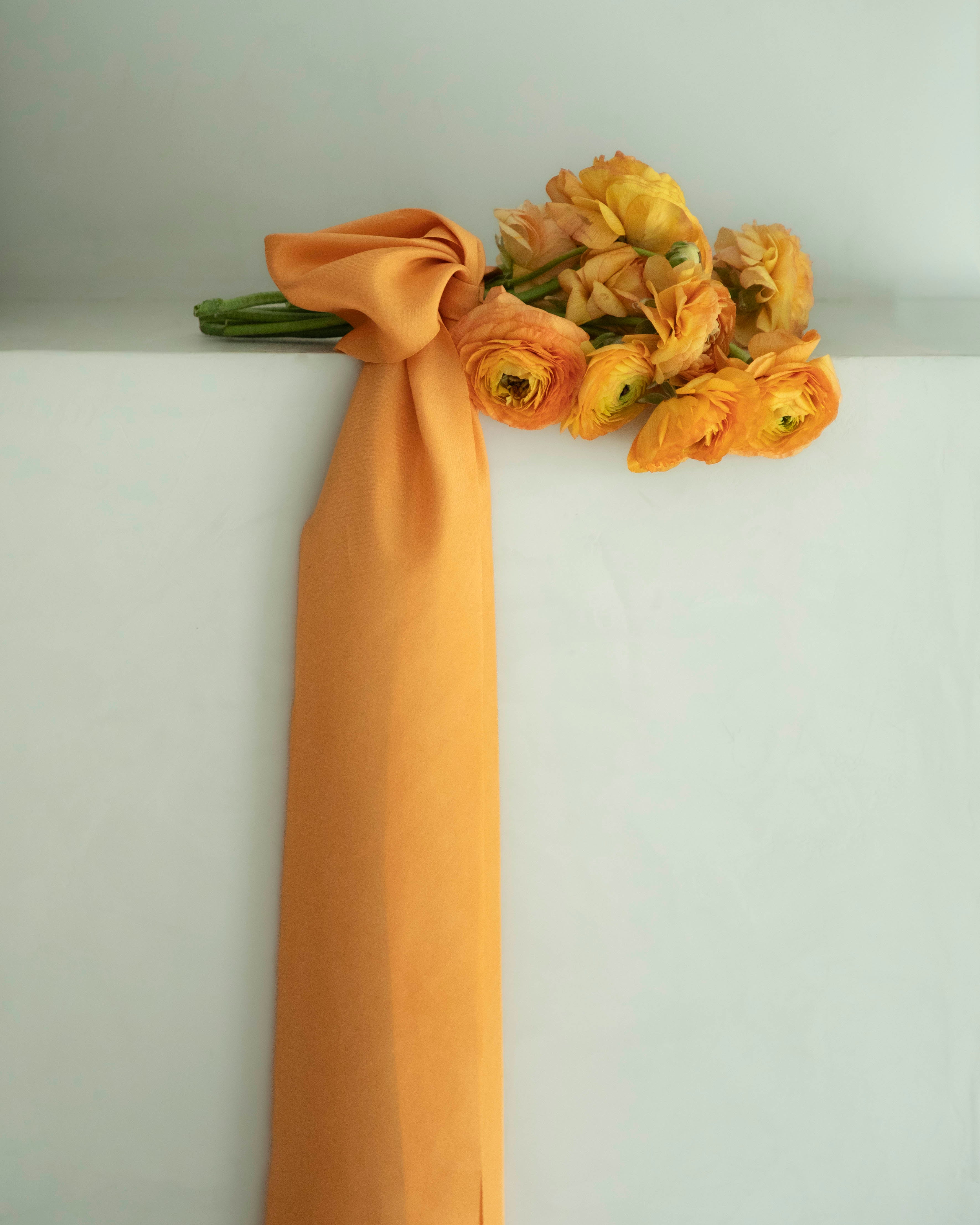 Orange ranunculus flower bouquet with orange silk ribbon