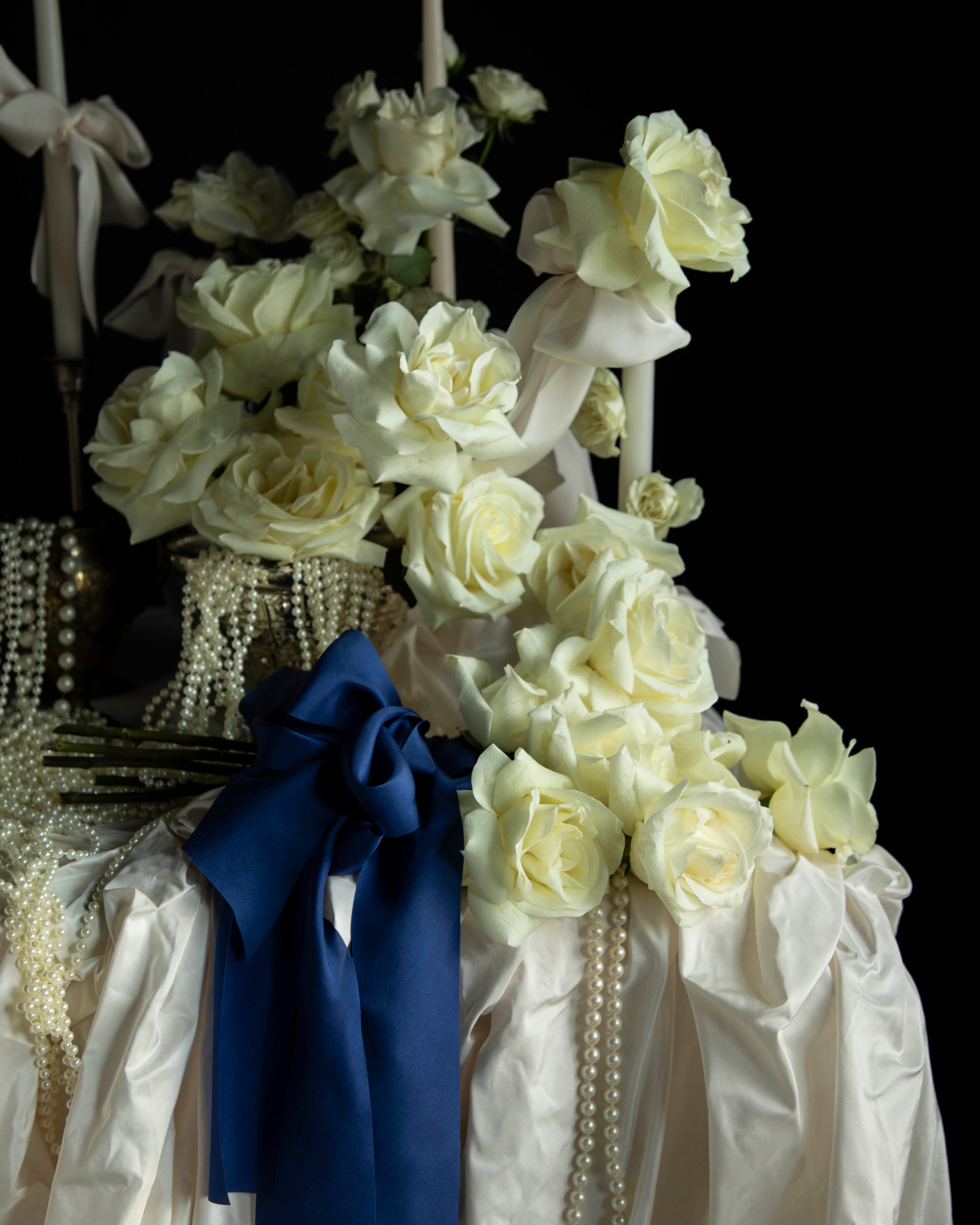 white roses and candles arrangement with draping pearls. bouquet of roses tied with cobalt silk ribbon.