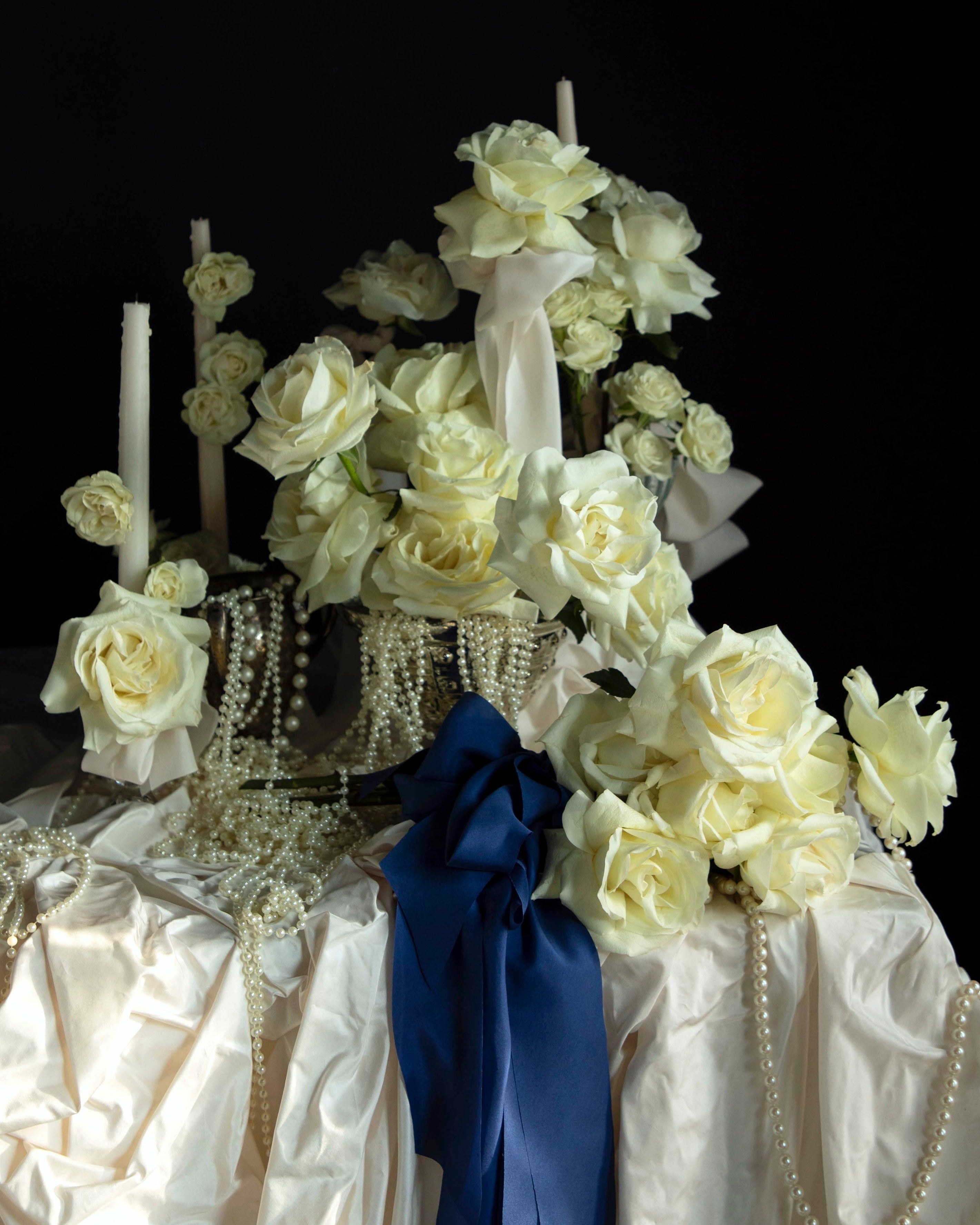 white roses and candles arrangement with draping pearls. bouquet of roses tied with cobalt silk ribbon.