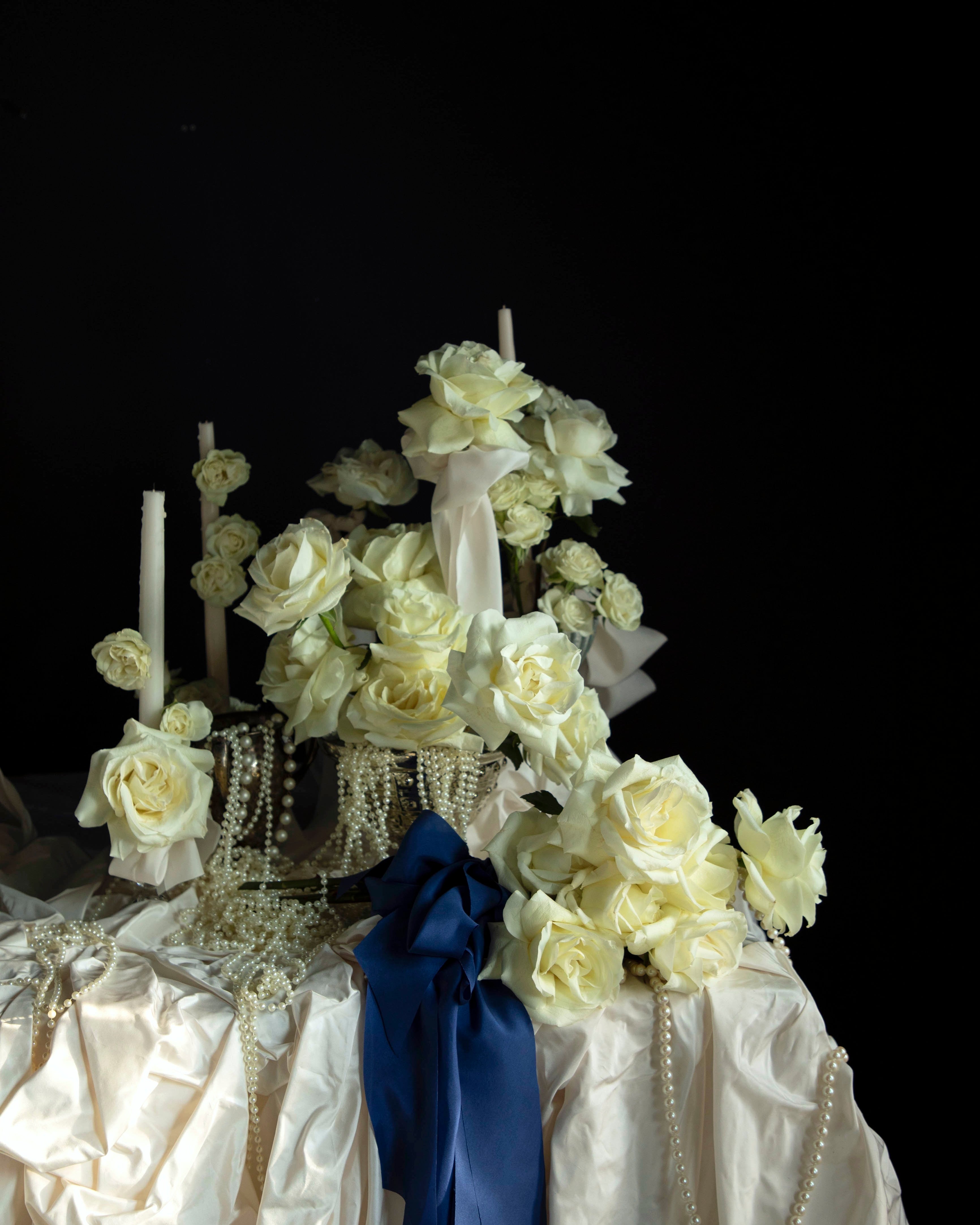 white roses and candles arrangement with draping pearls. bouquet of roses tied with cobalt silk ribbon.
