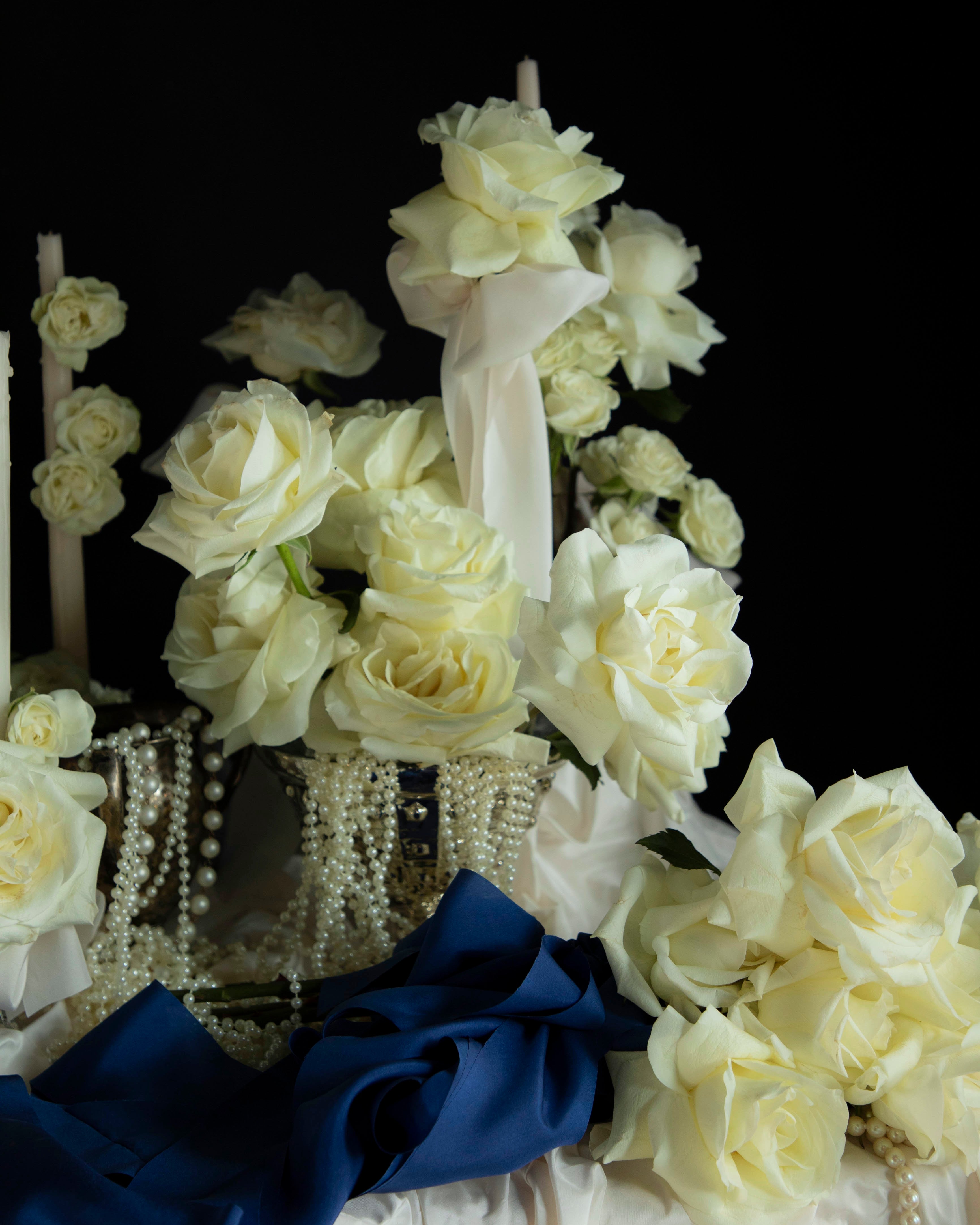 Decorative shoe with white flowers and a blue bow on a black background