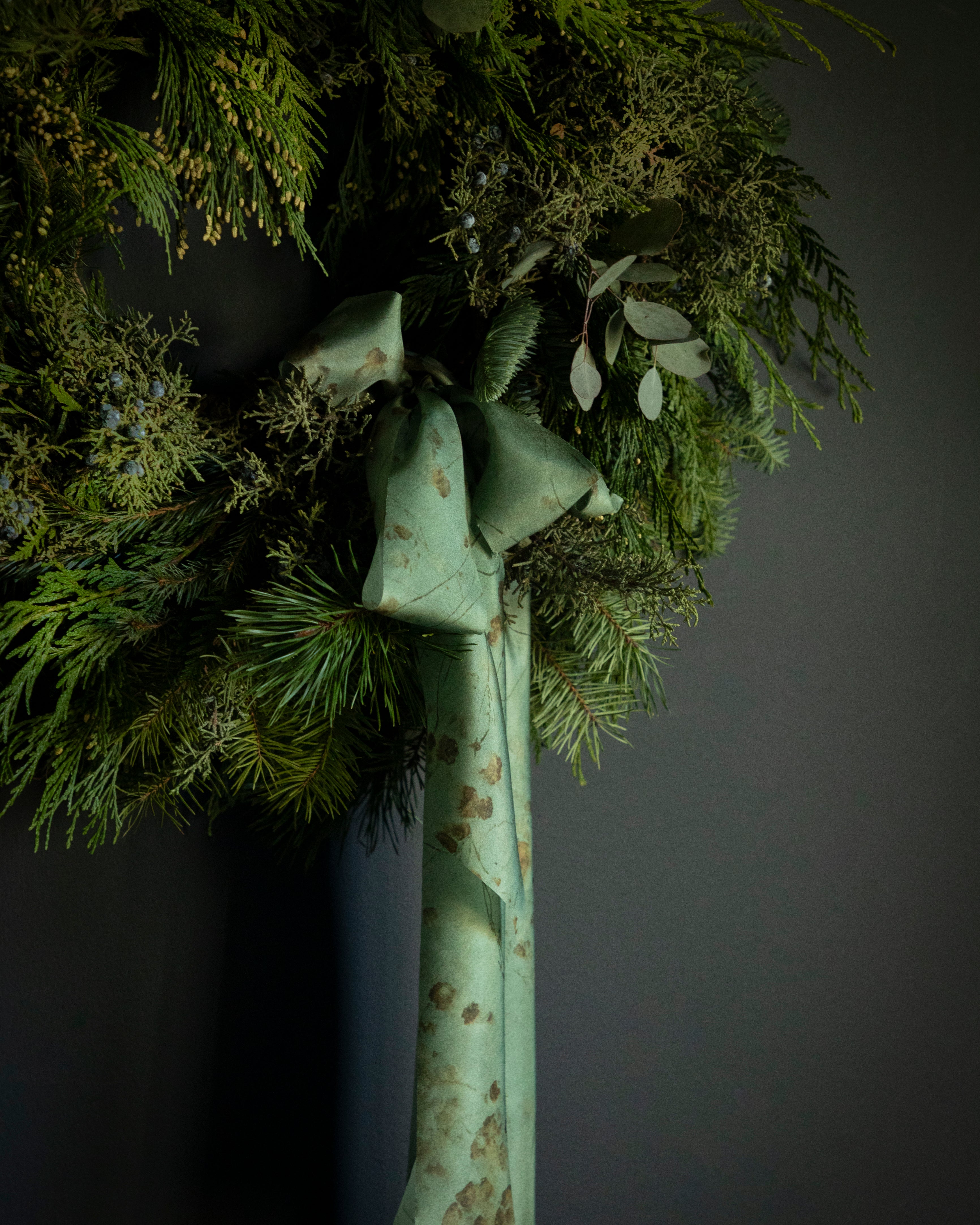 evergreen wreath for the holidays tied with silk ribbon bow. Eco-friendly silk ribbons with nature-inspired patterns, perfect for unique gift wrapping and tying market bouquets, crafted from sustainable materials