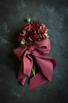 close up of flowers tied with red ribbon bow on a black surface
