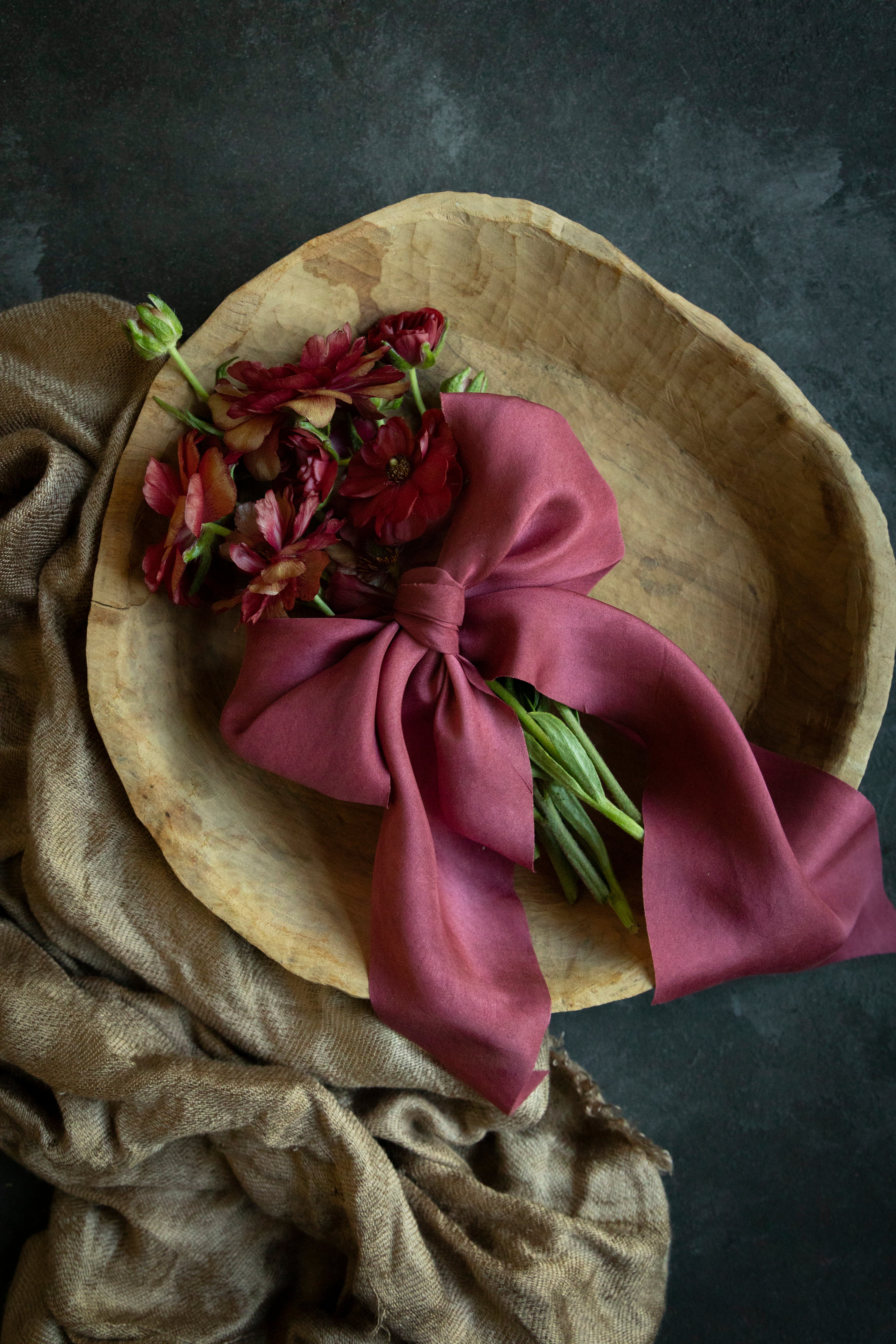 flowers in a wood bowl tied with red silk ribbon bow