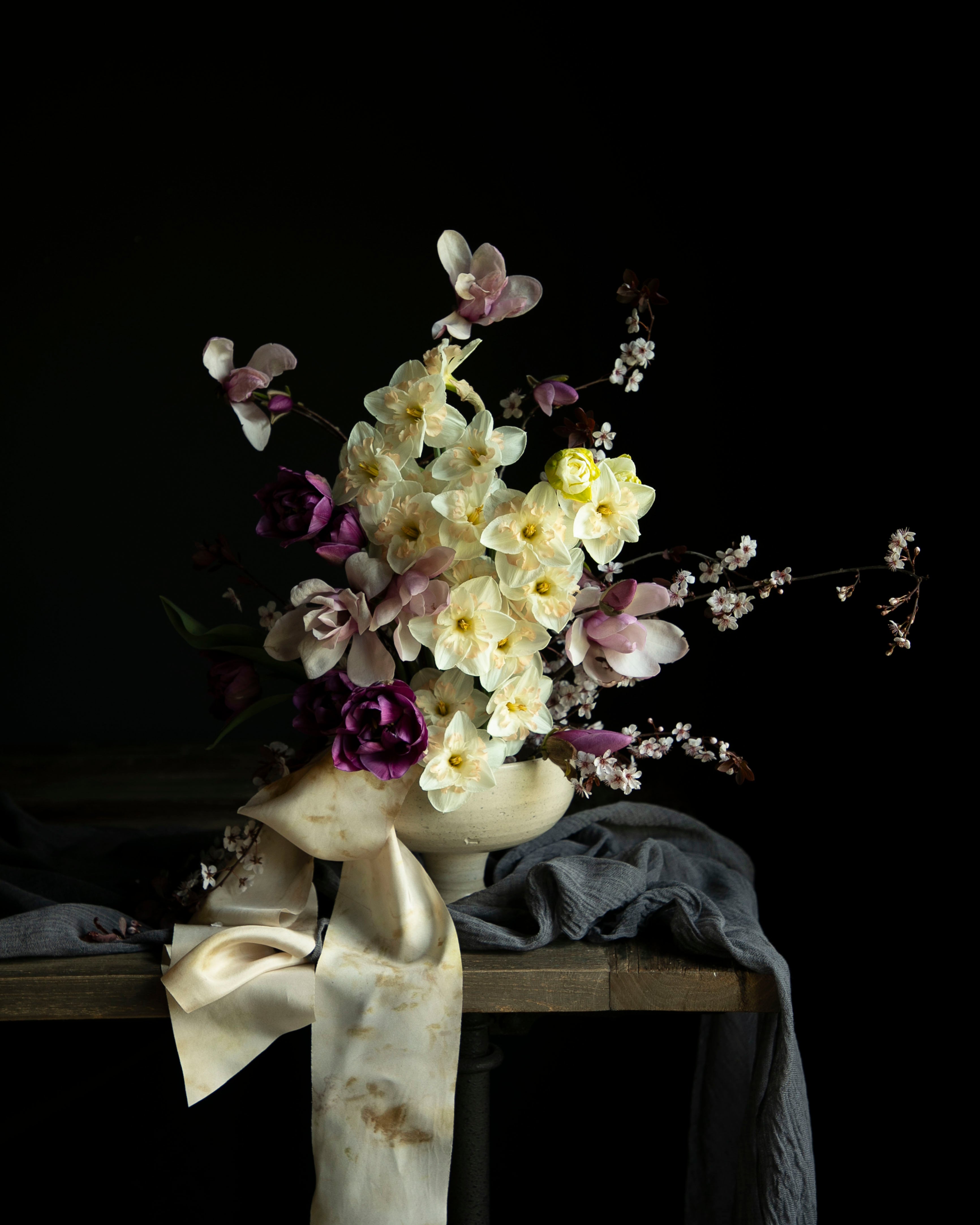 daffidols, magnolia branches, and tulip Bouquet in a vase on a dark background