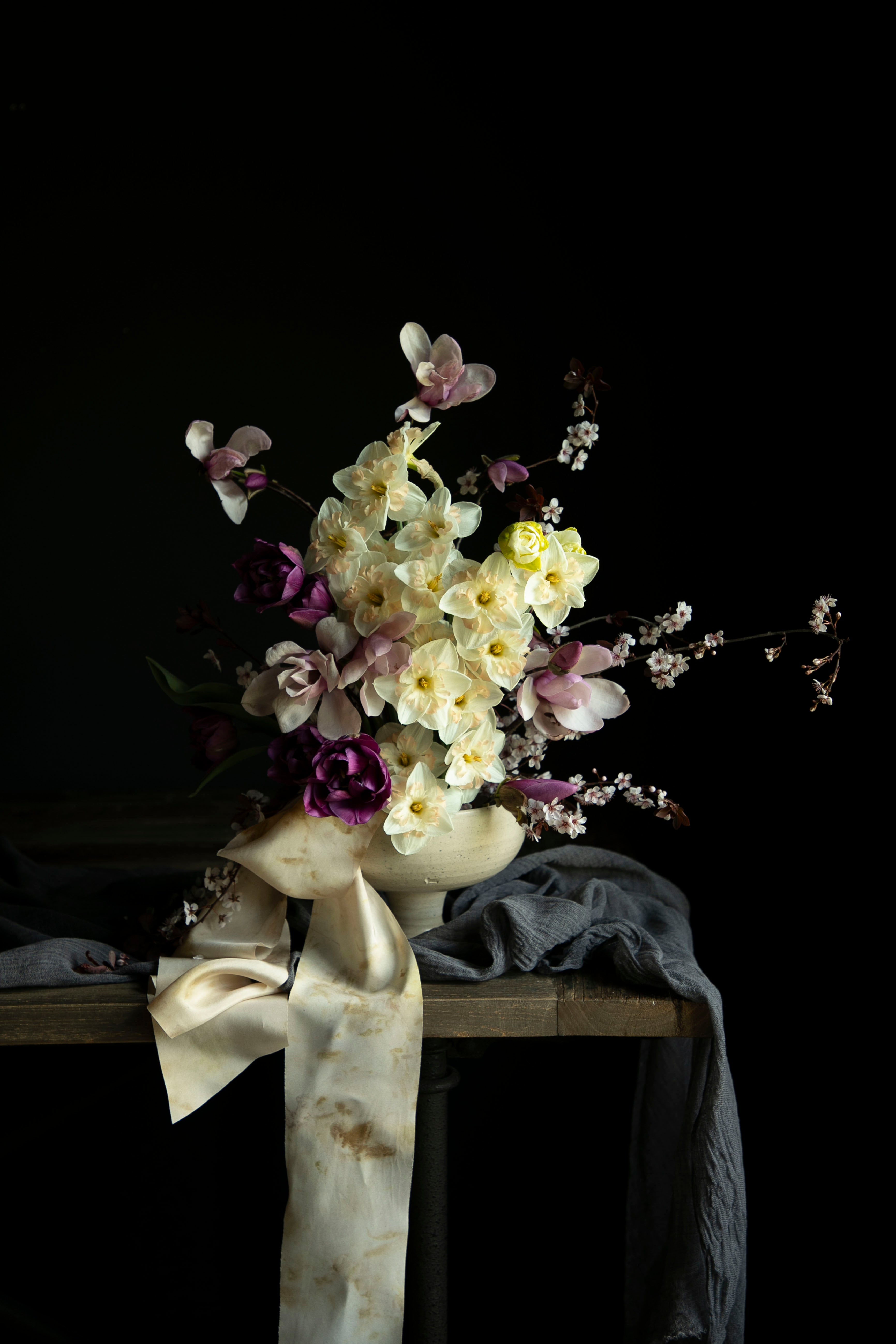 daffidols, magnolia branches, and tulip Bouquet in a vase on a dark background