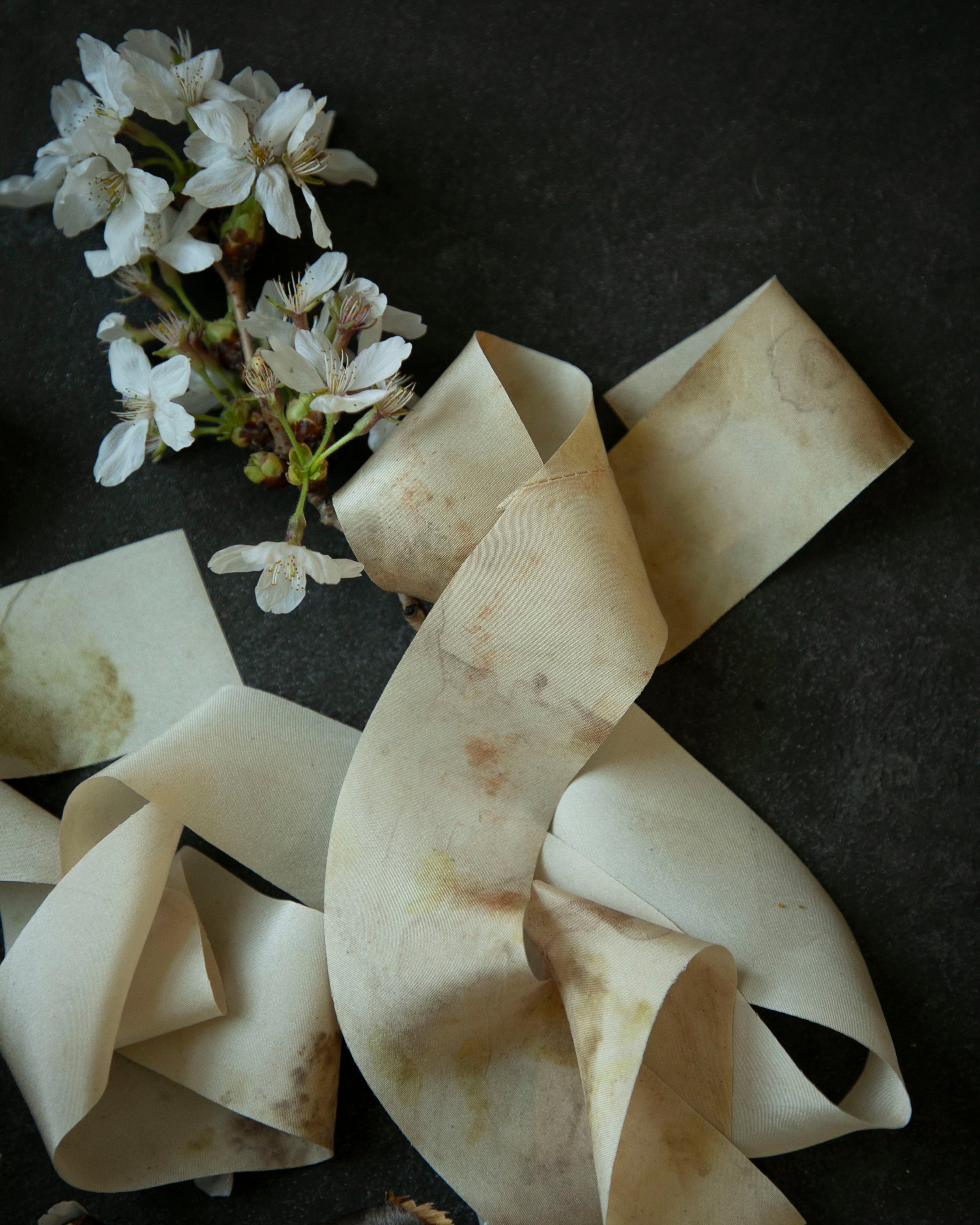 Ruffled silk ribbons with a small bouquet of white flowers on a dark surface