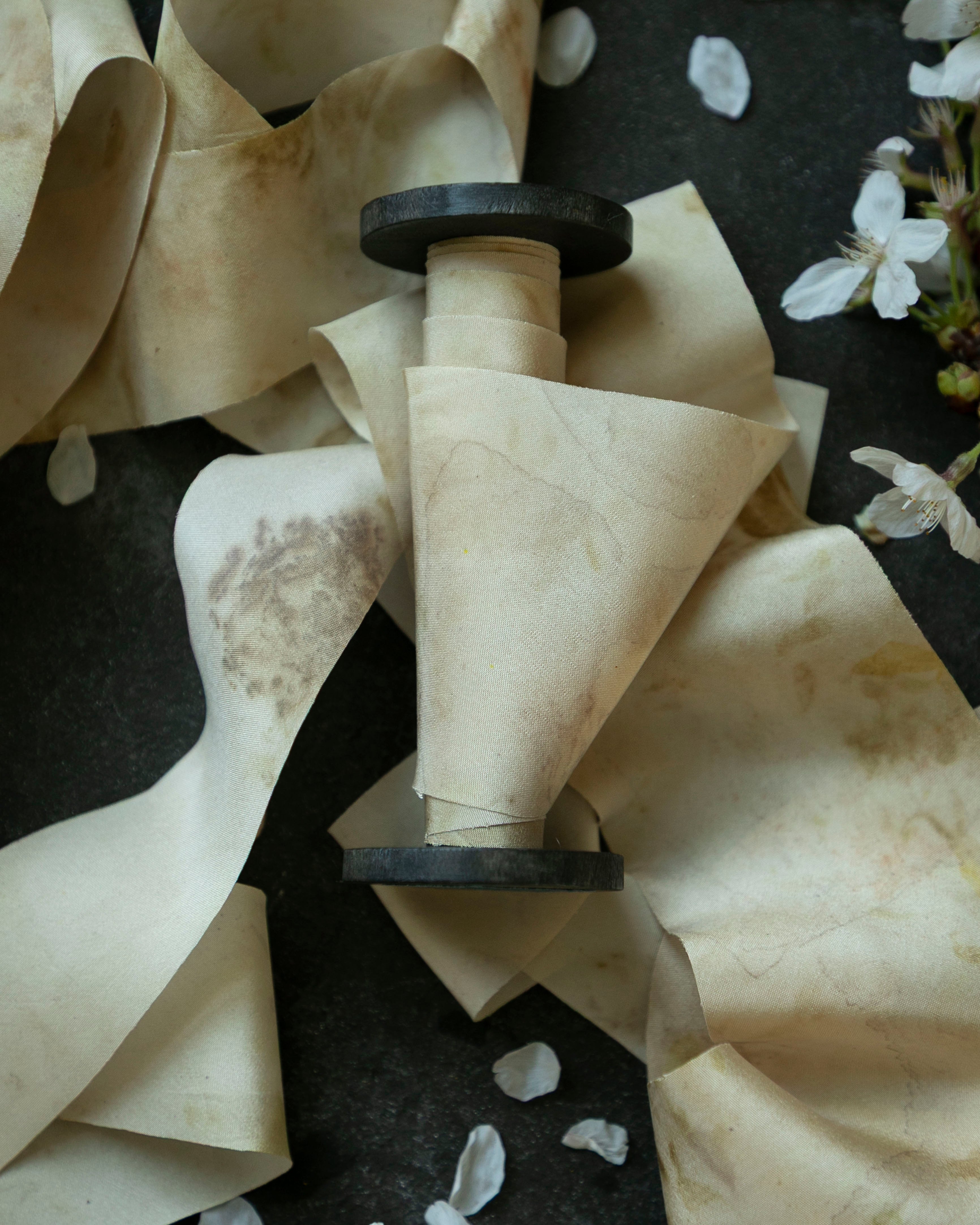 spool of the best silk ribbon on a dark surface with white flowers.