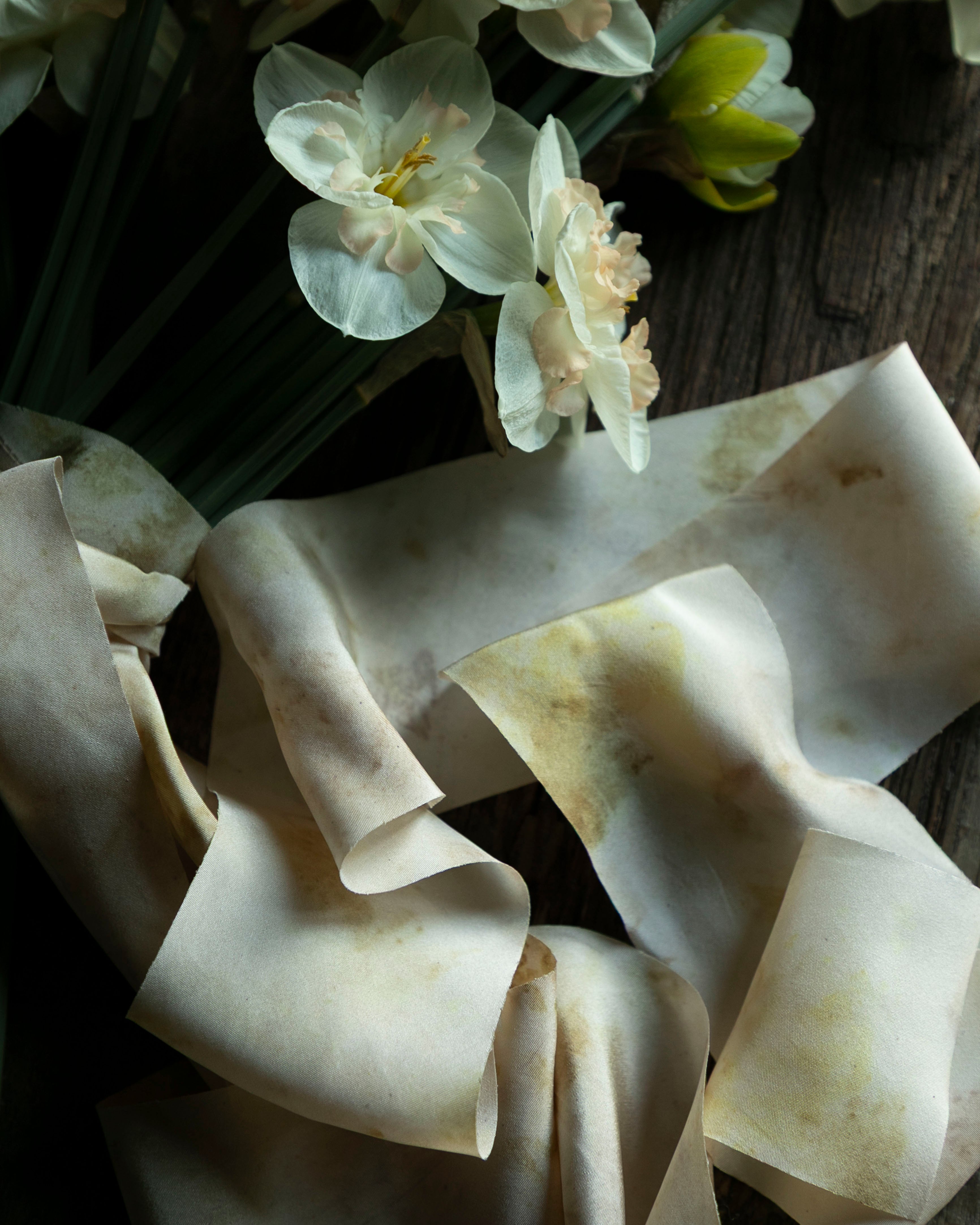 Bouquet of white flowers with a crumpled white paper or fabric on a wooden surface.
