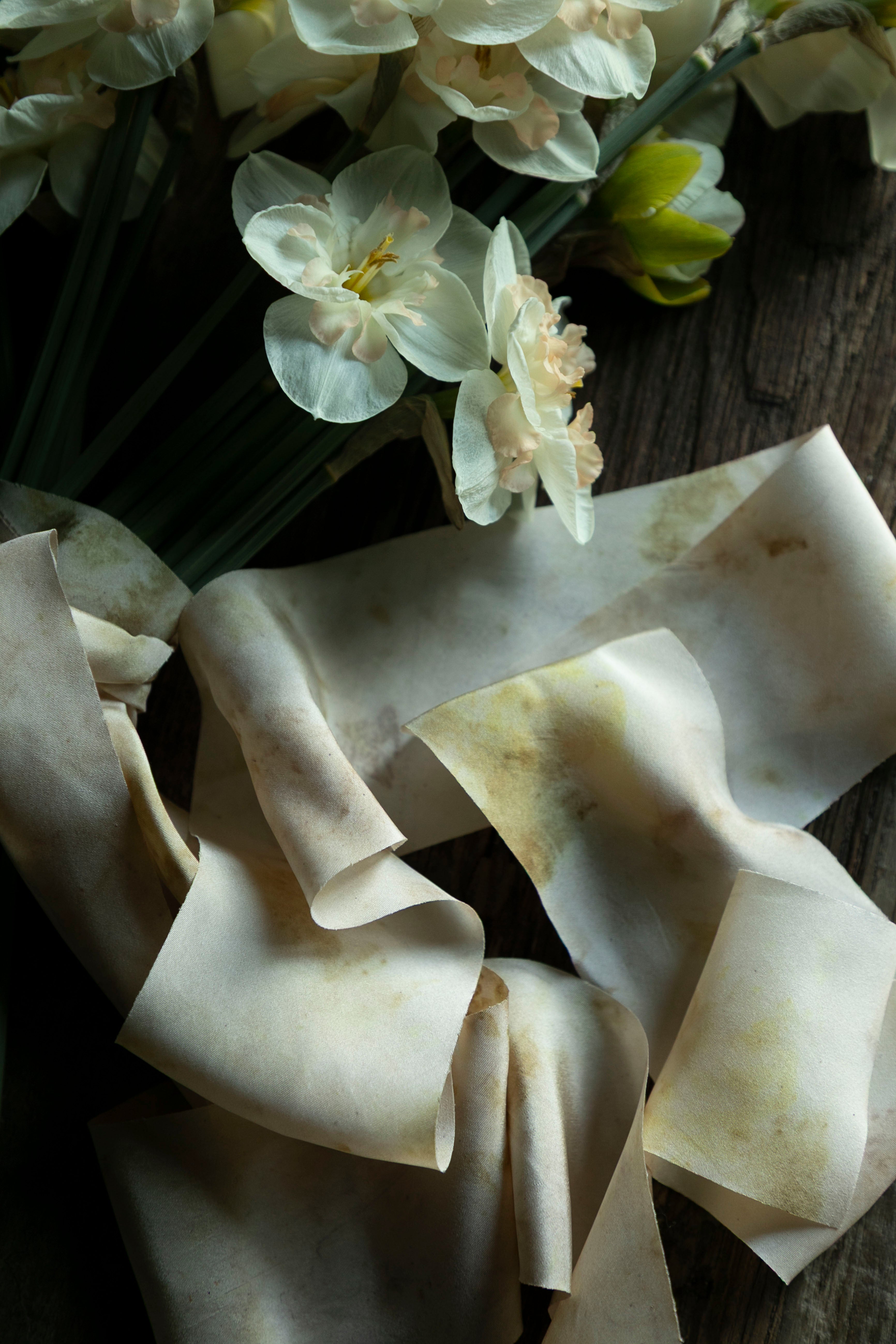 Bouquet of white flowers with a crumpled white paper or fabric on a wooden surface.