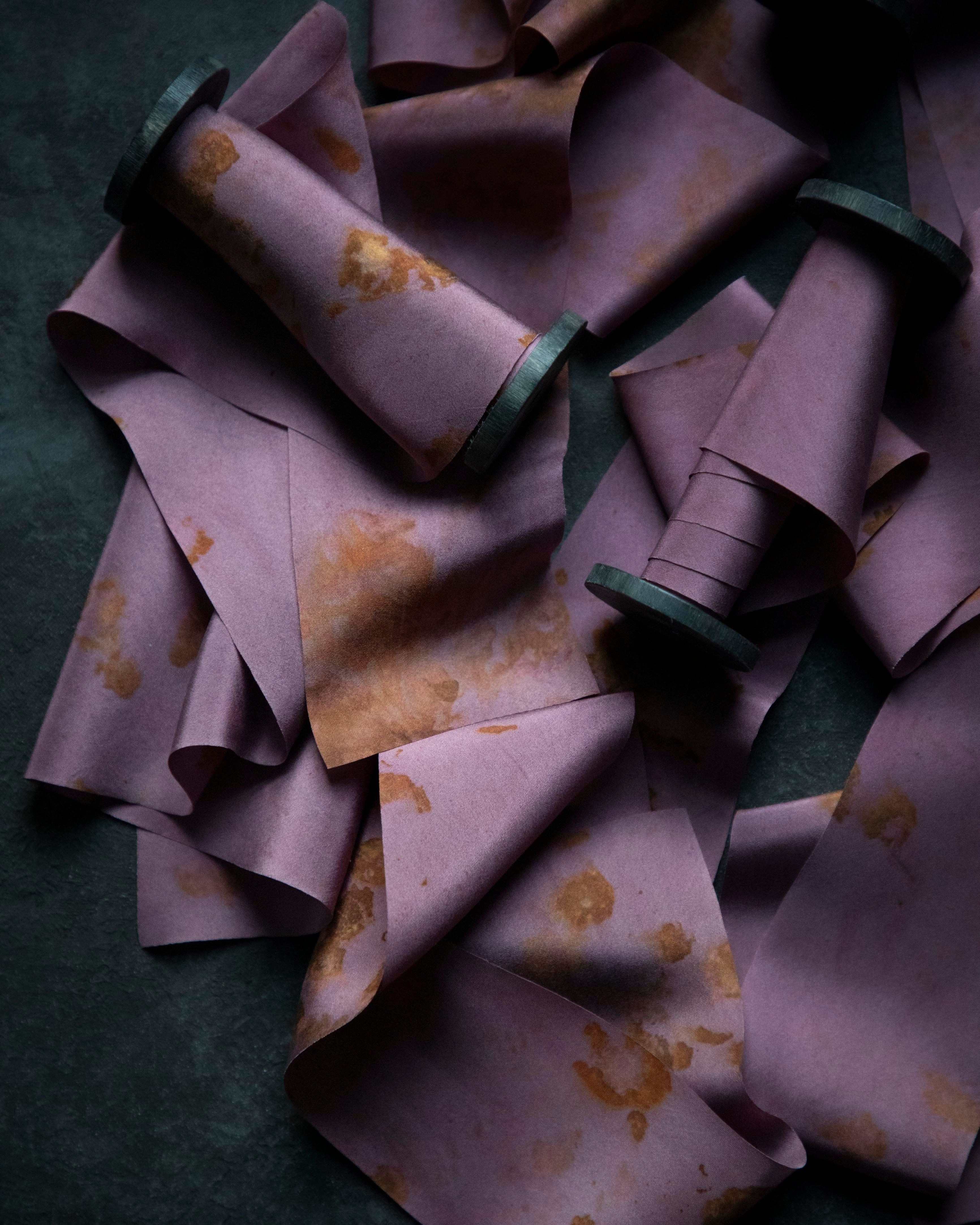 Purple fabric with brown spots on a dark green background