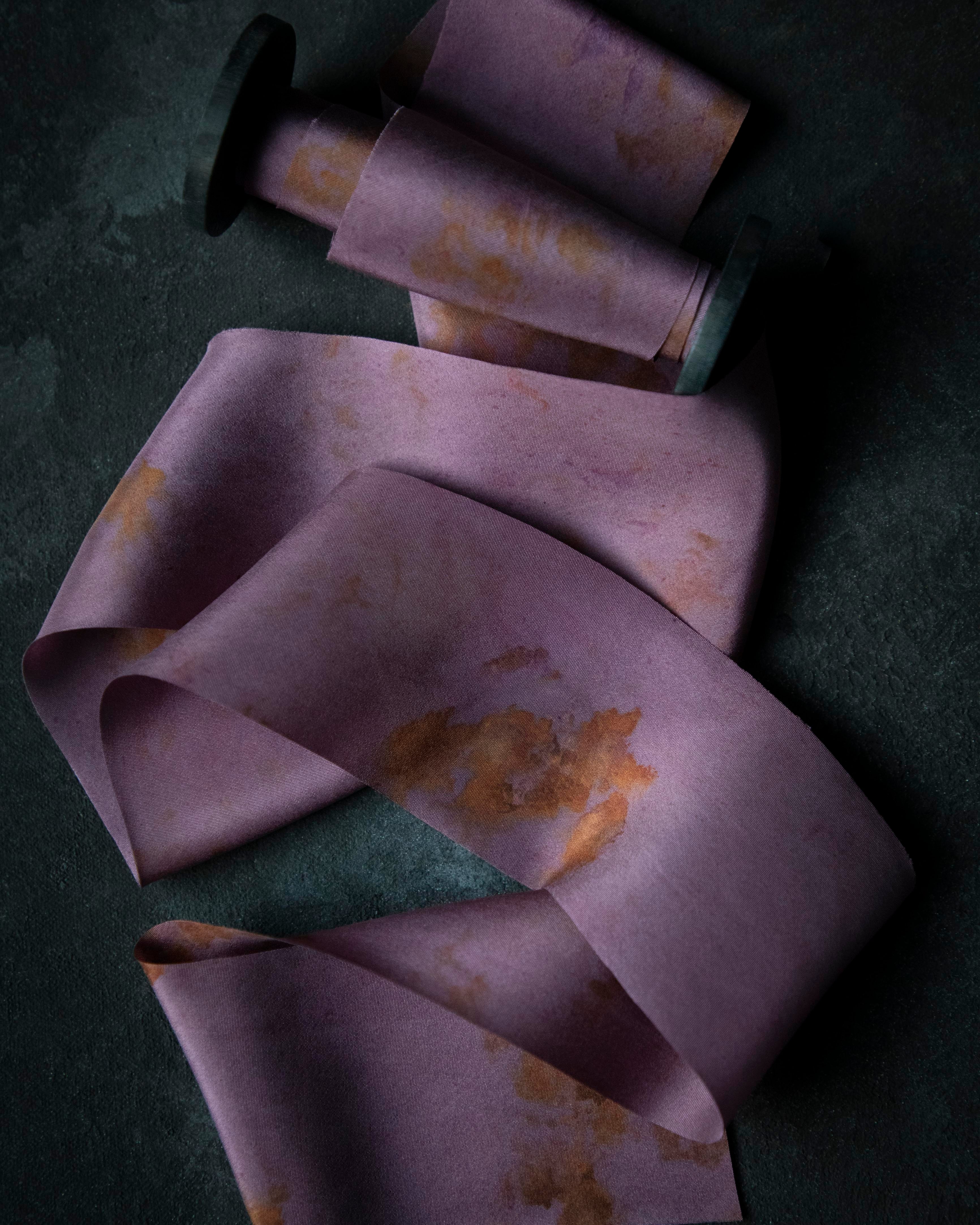 Purple fabric with yellow eco-prints on a dark surface
