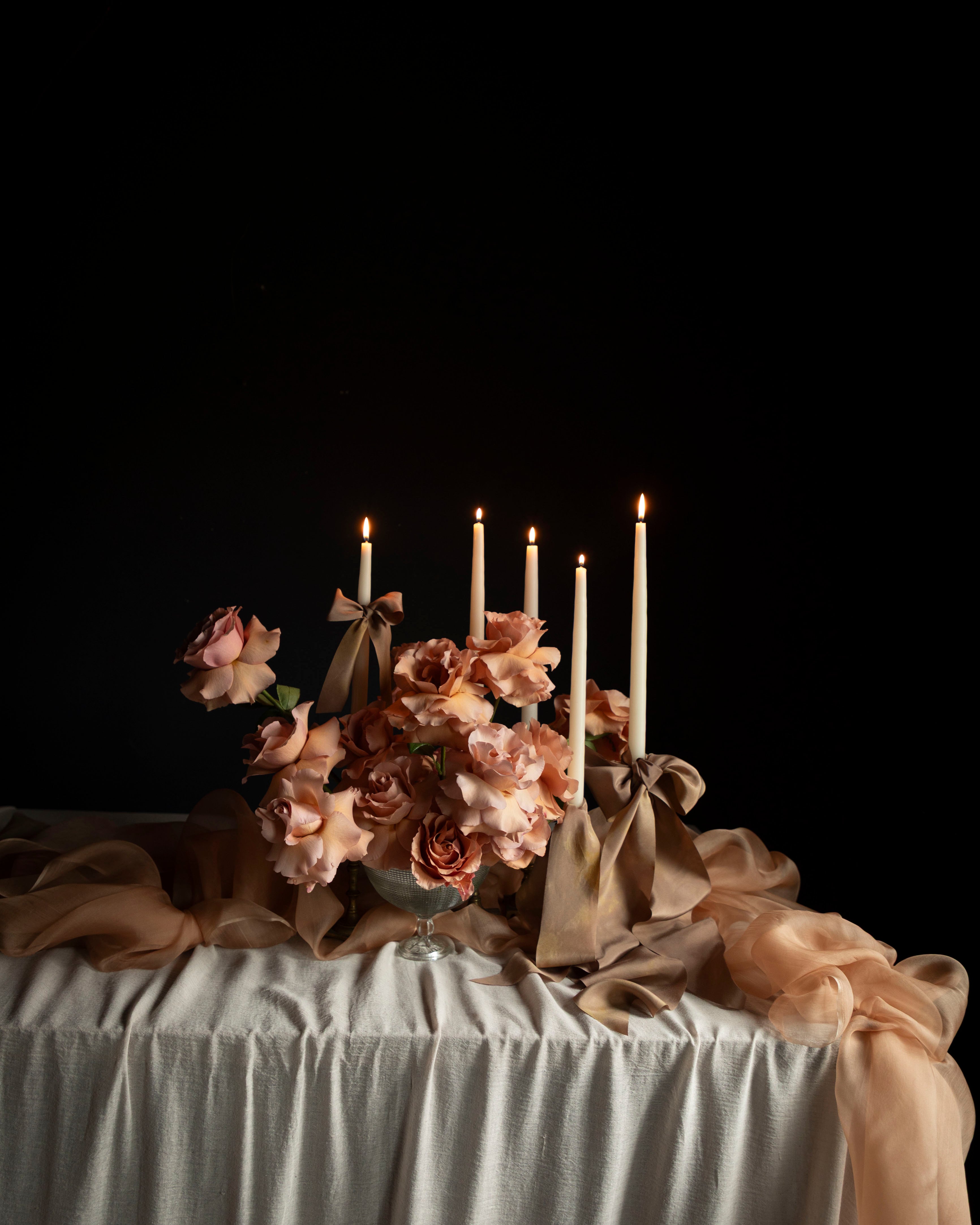 Decorative table setting with flowers, candles, and a dark background