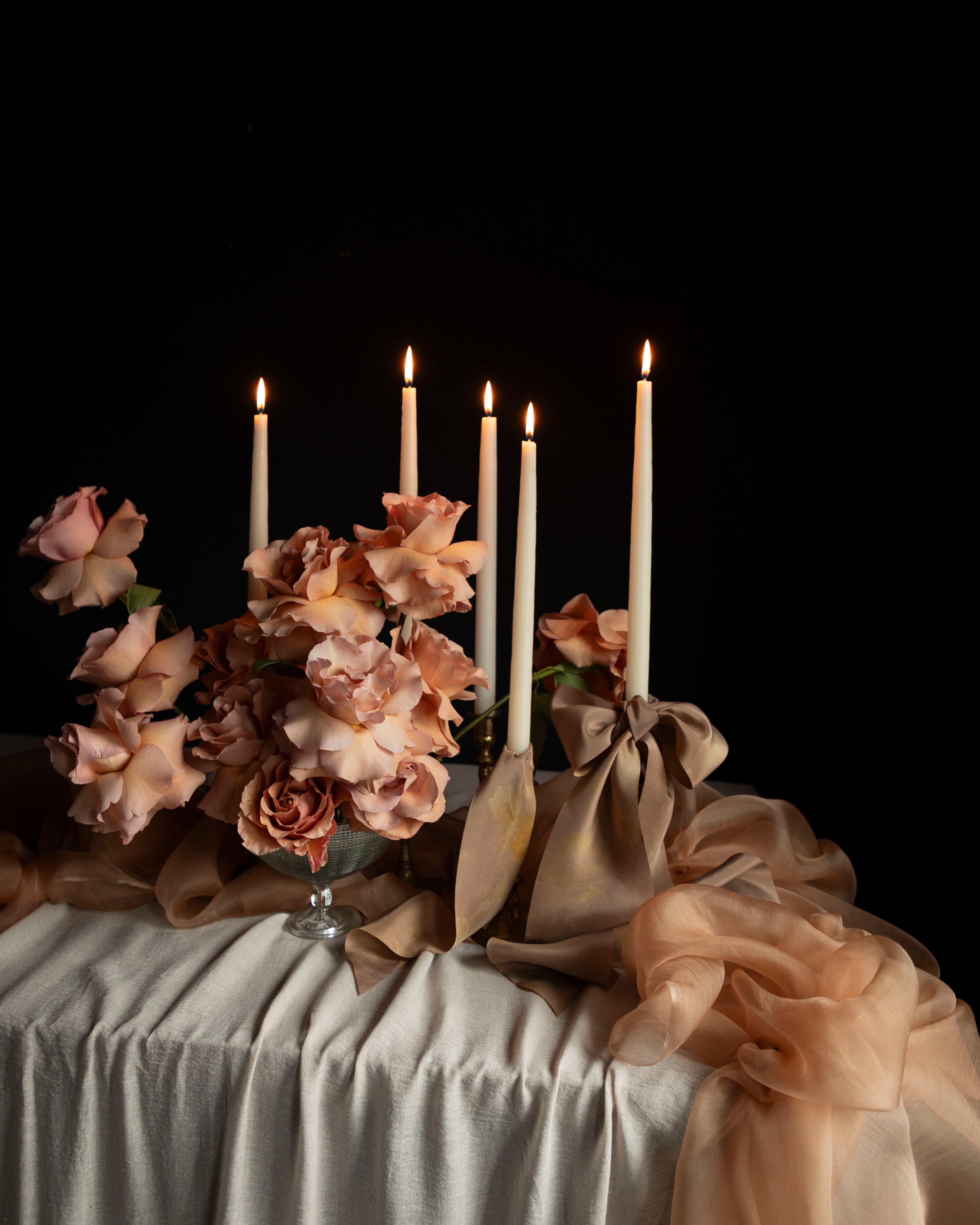 Decorative table setting with candles and flowers on a dark background
