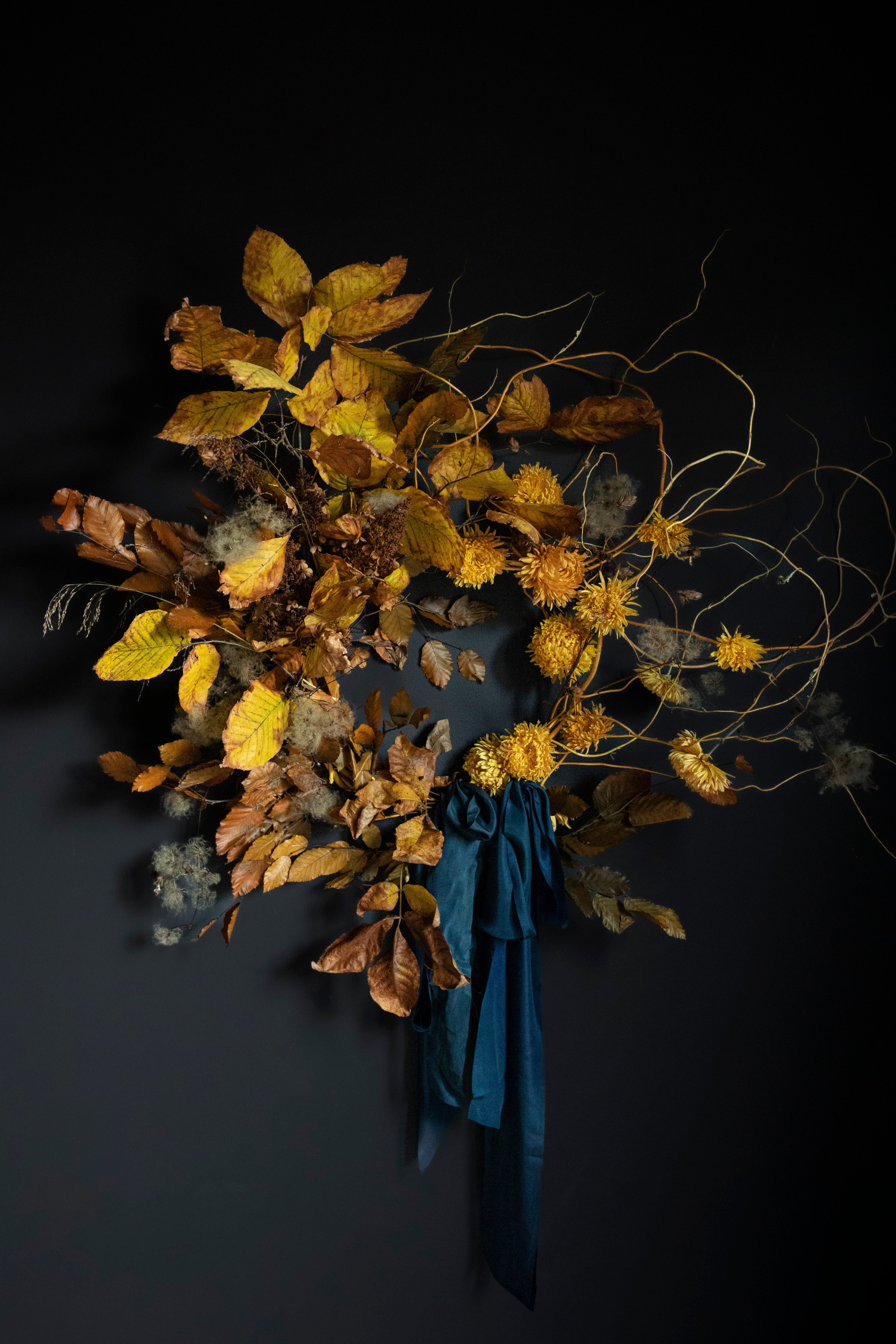 Dried floral arrangement with a blue ribbon on a dark background