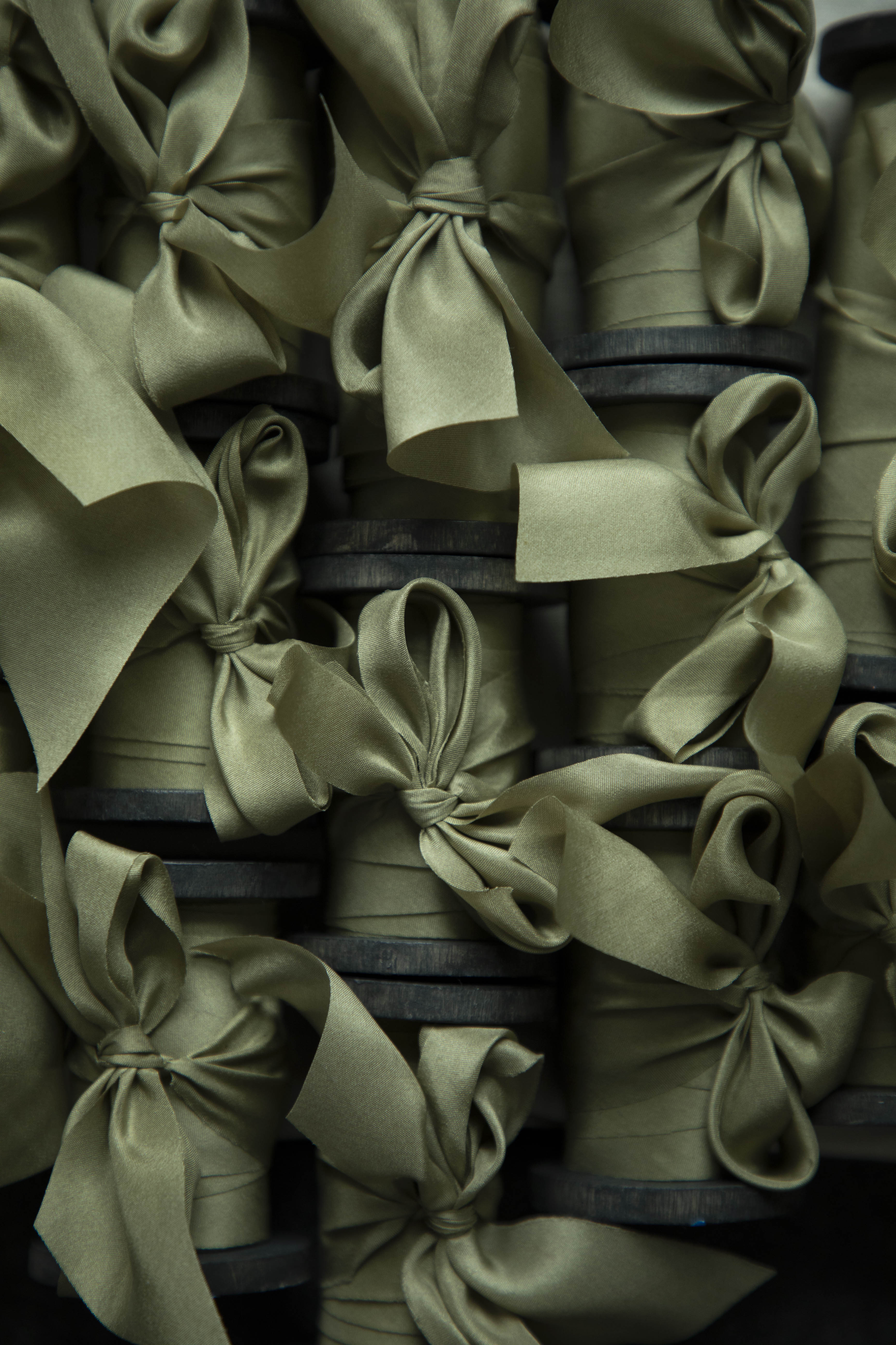 Stack of green silk ribbons on vintage style wood spools items with ribbons on a dark background