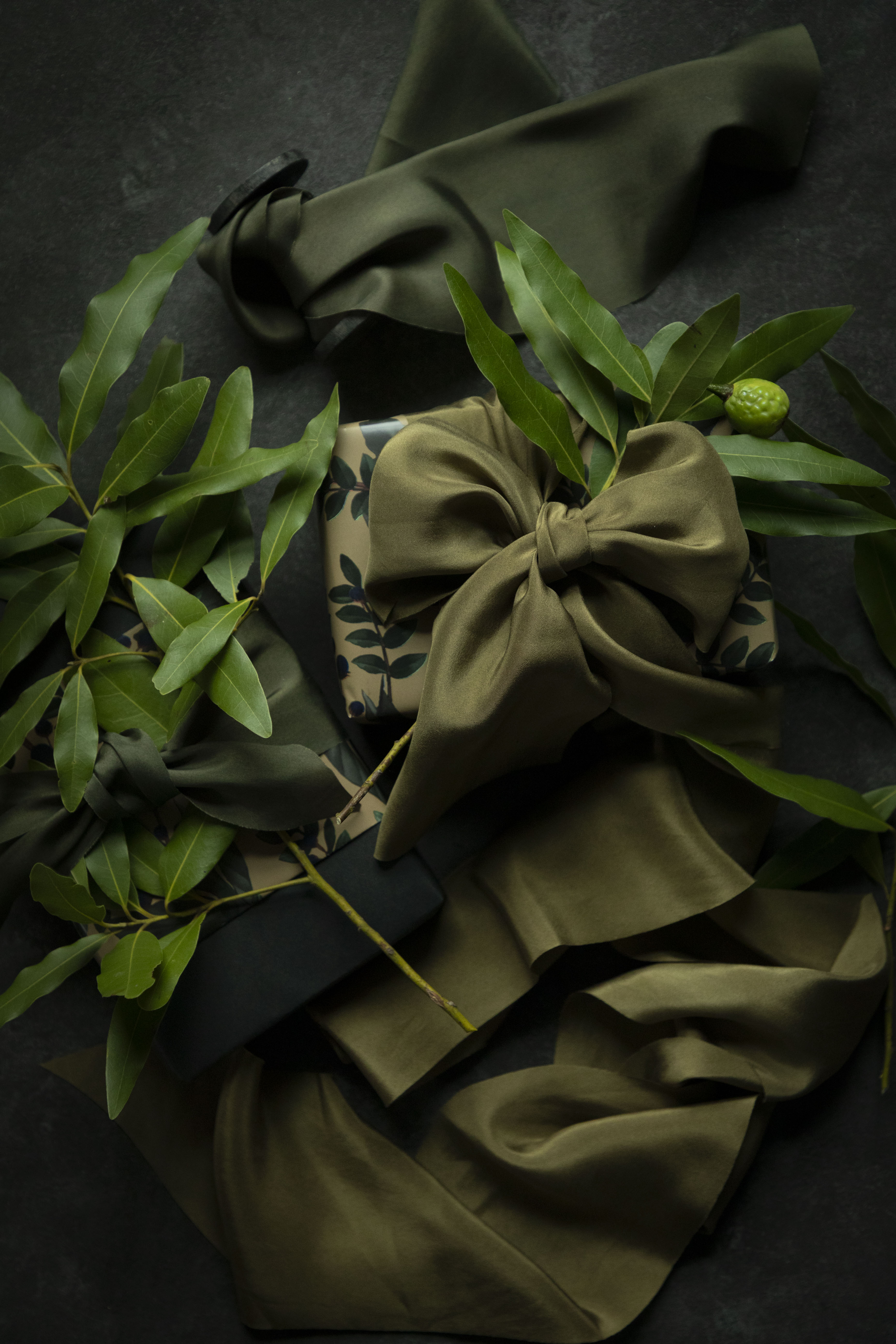 Green fabric with a bow and leaves on a dark background