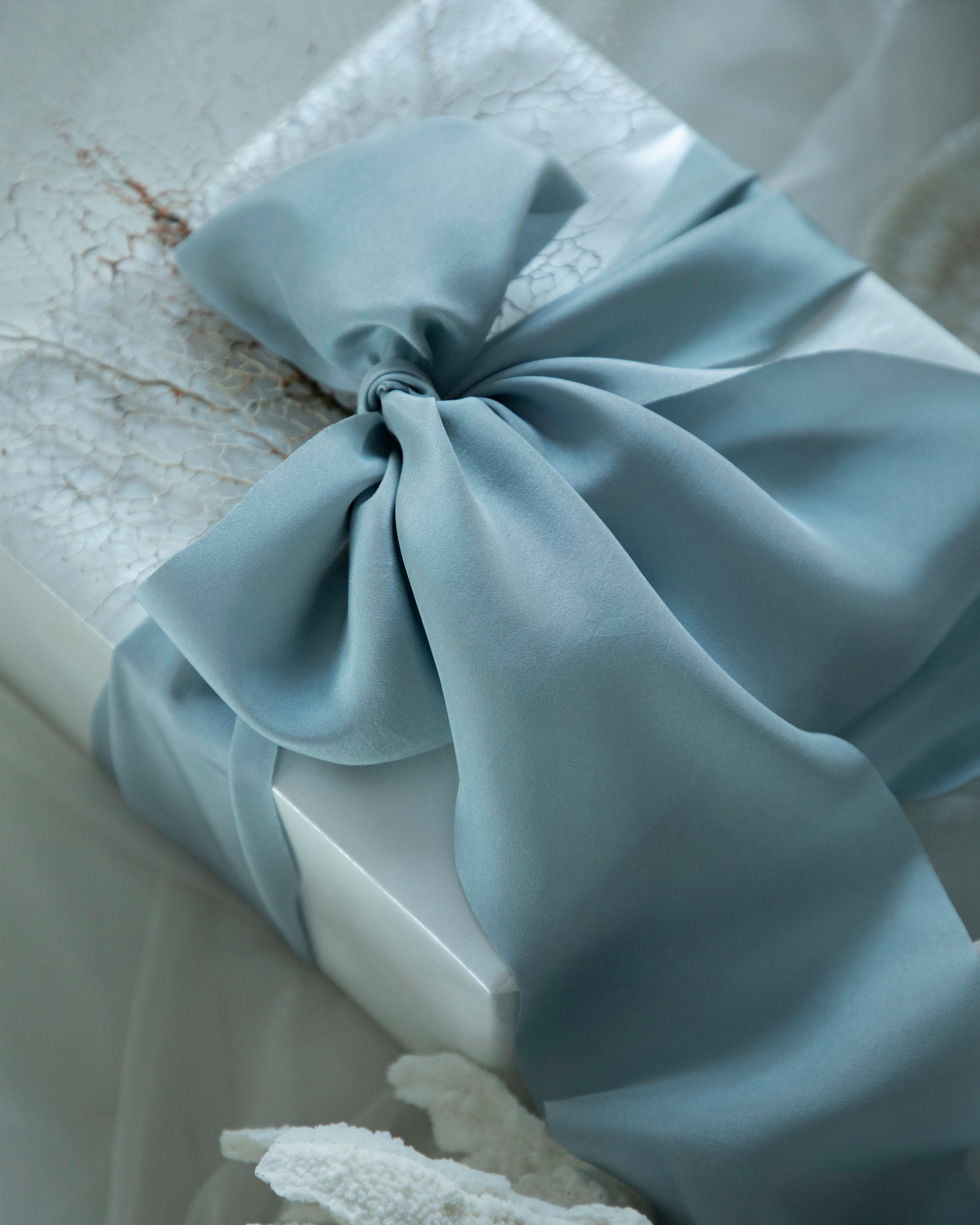 French blue bow on a white box with a textured background. Luxury gift wrapping inspiration