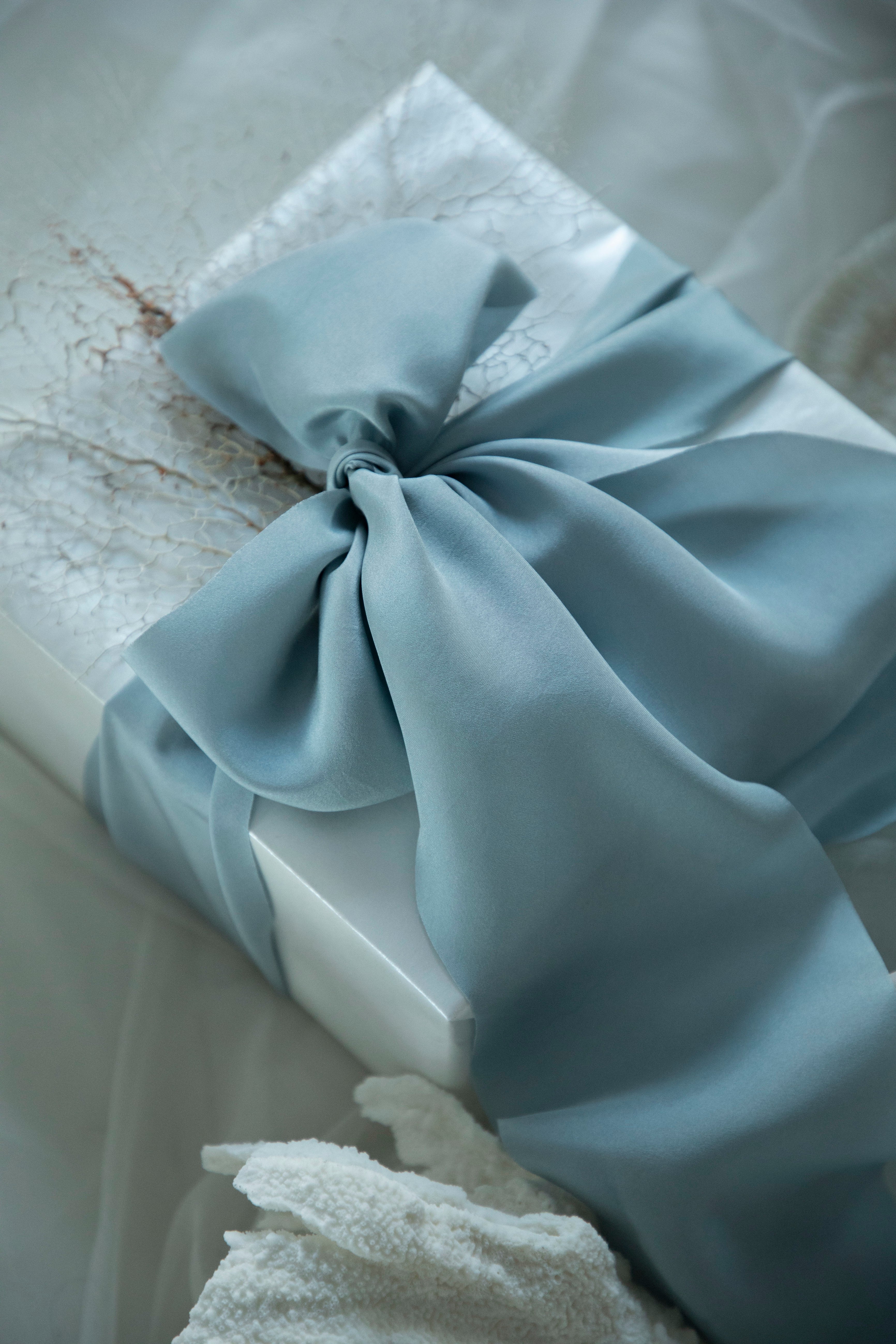 French blue bow on a white box with a textured background. Luxury gift wrapping inspiration