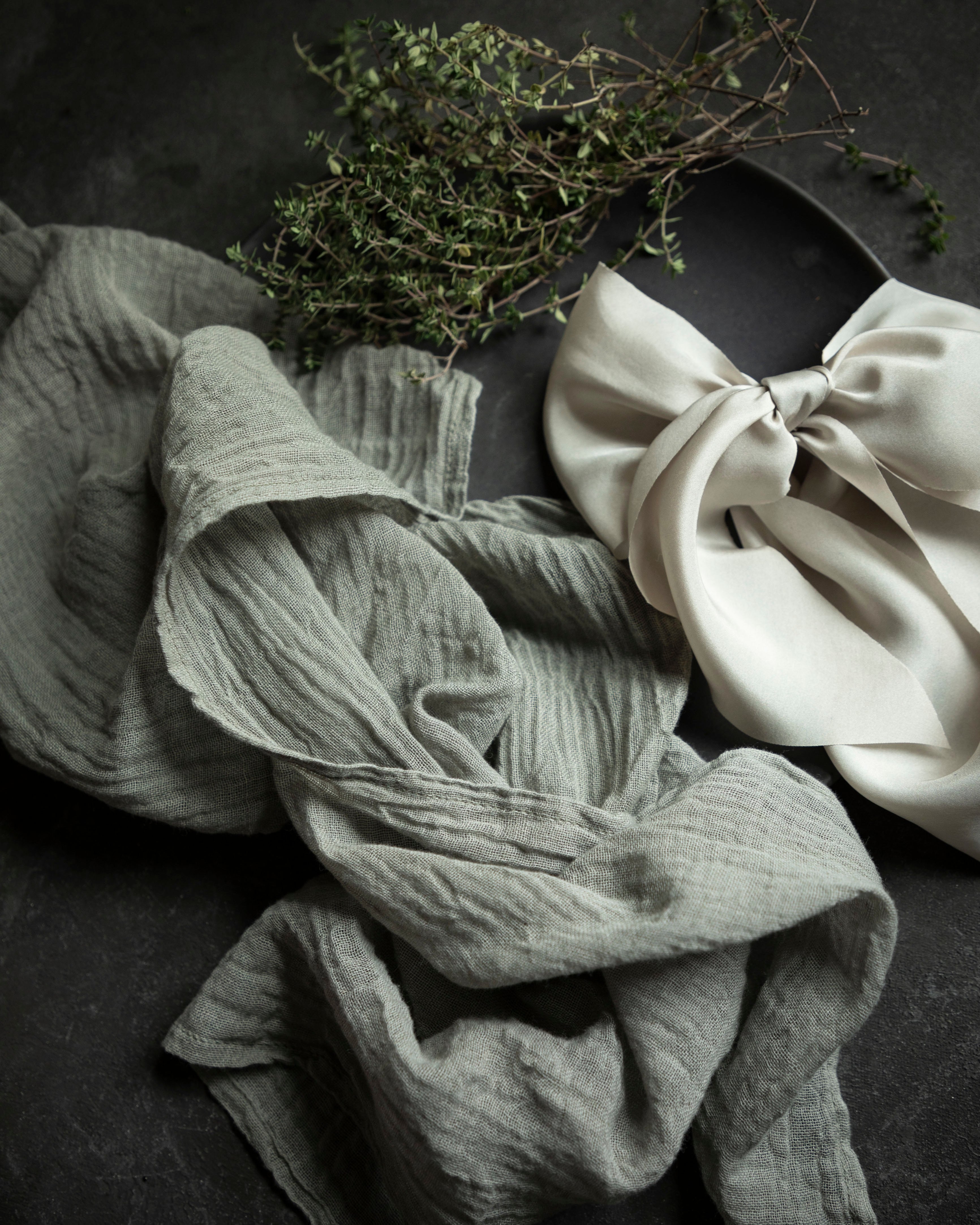 Folded napkin in gray and white on a dark surface with greenery.