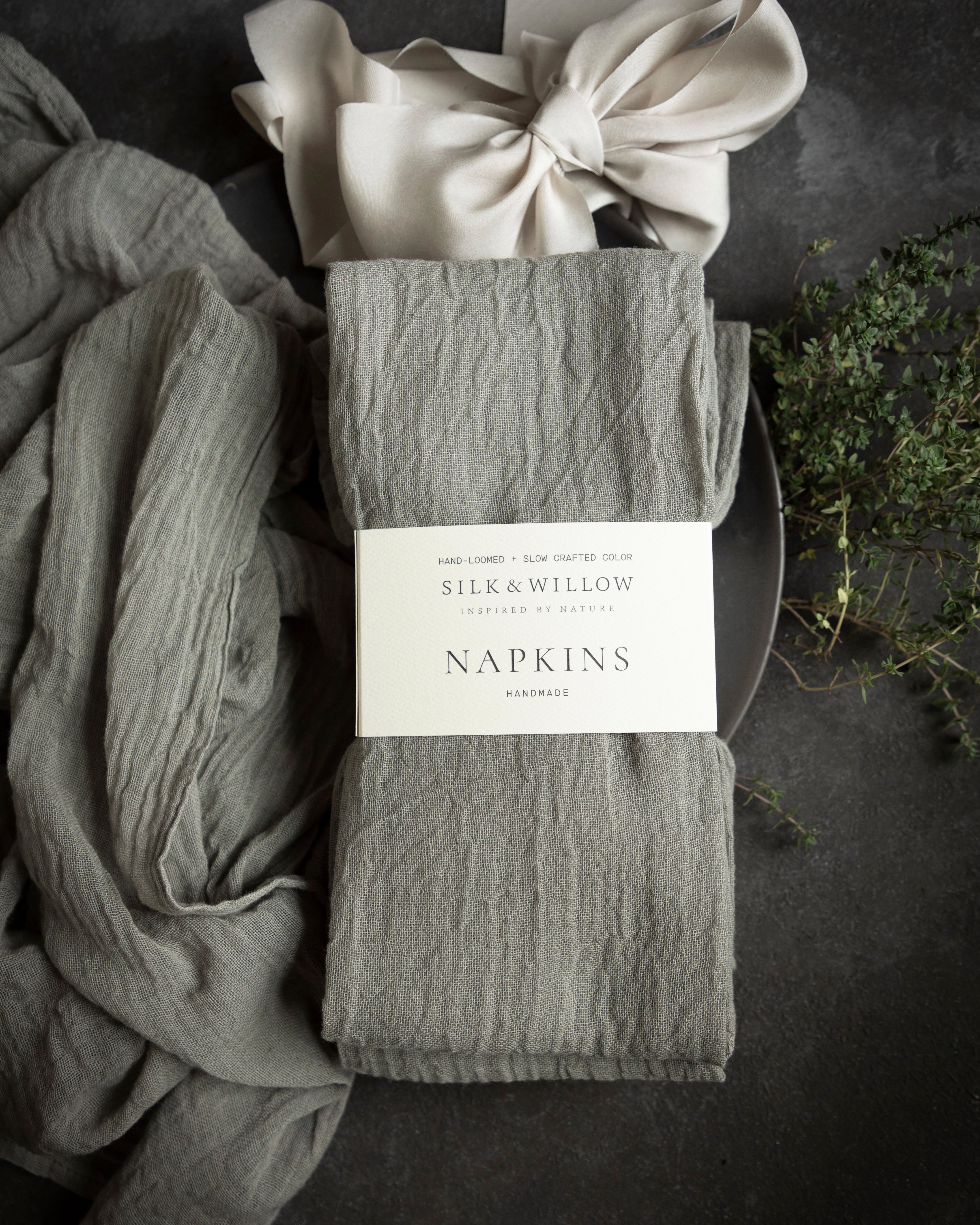 Packaged gray napkins with a bow on a dark surface, featuring the brand 'Silk & Willow'.