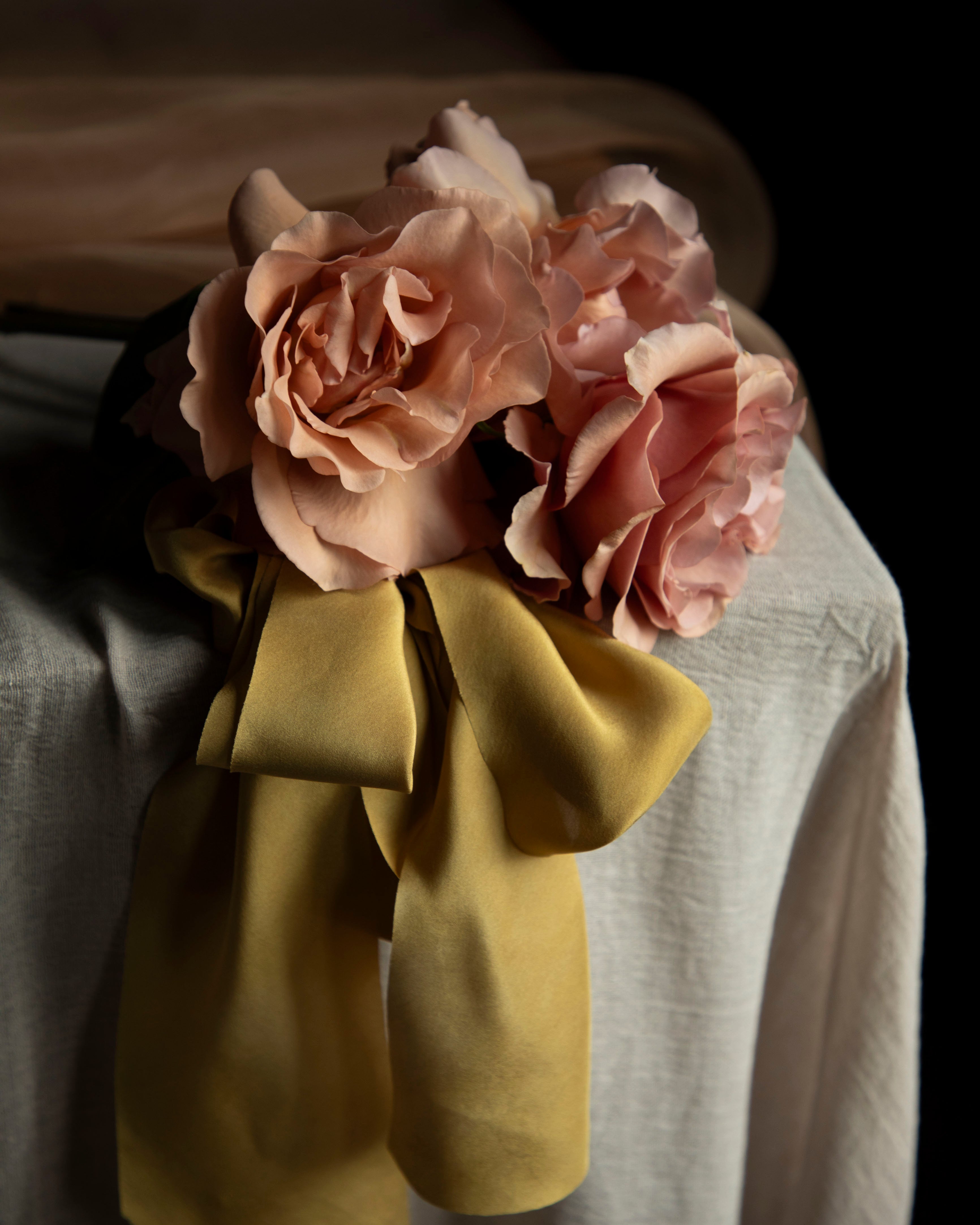 Floral arrangement with pink roses and a yellow bow on a neutral background