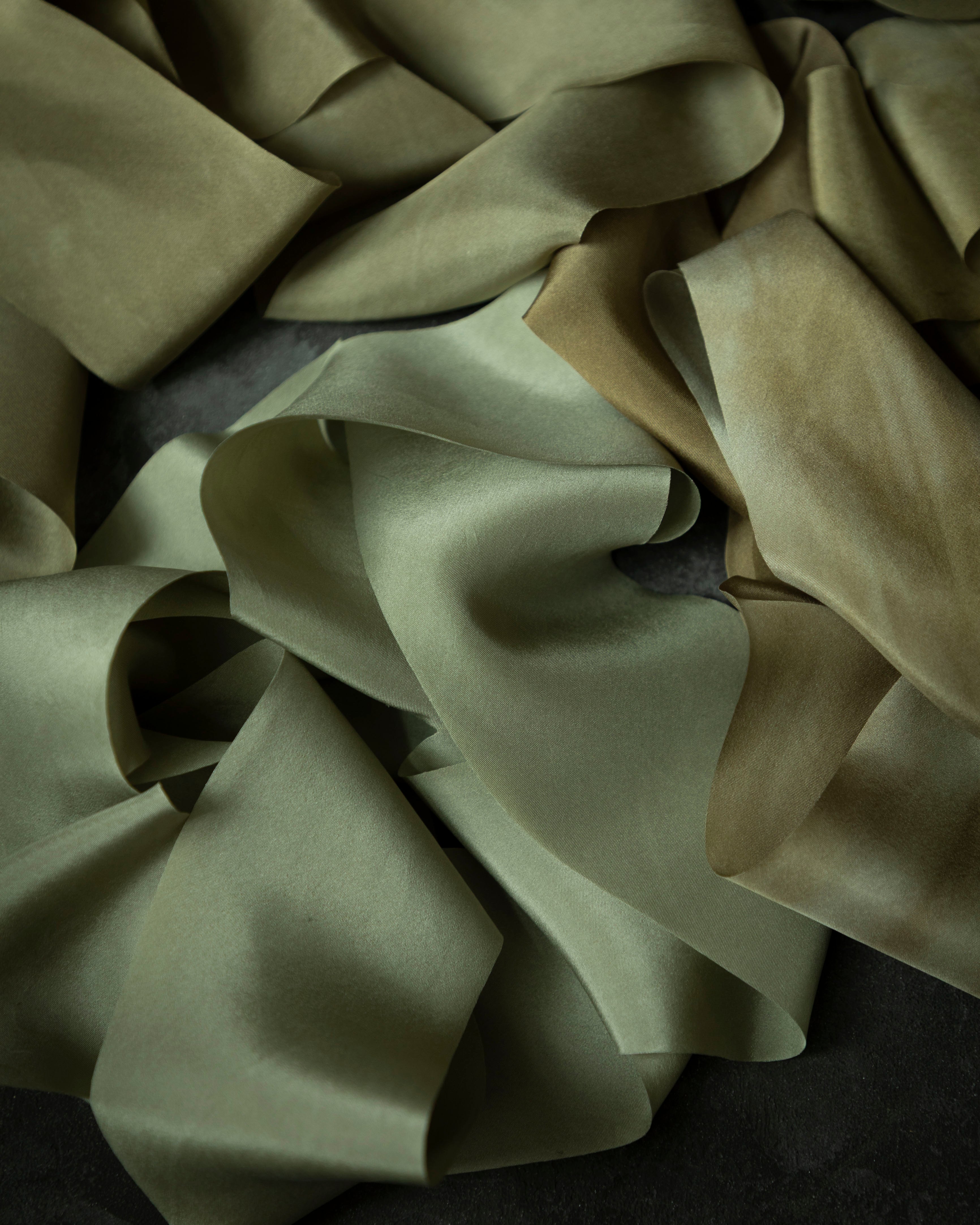 Close-up of green silk ribbon on a dark background