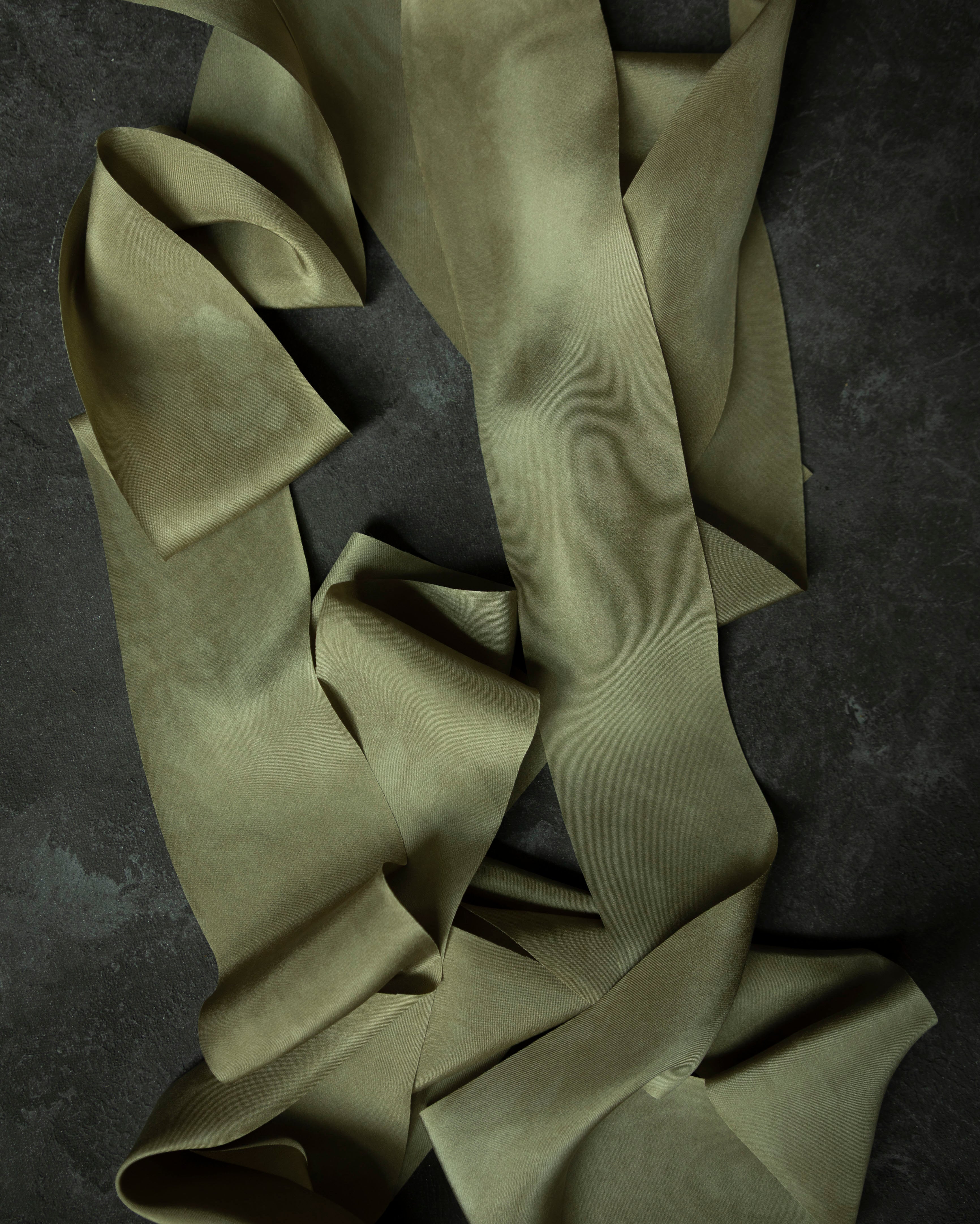 hand dyed green silk ribbon on a dark textured surface