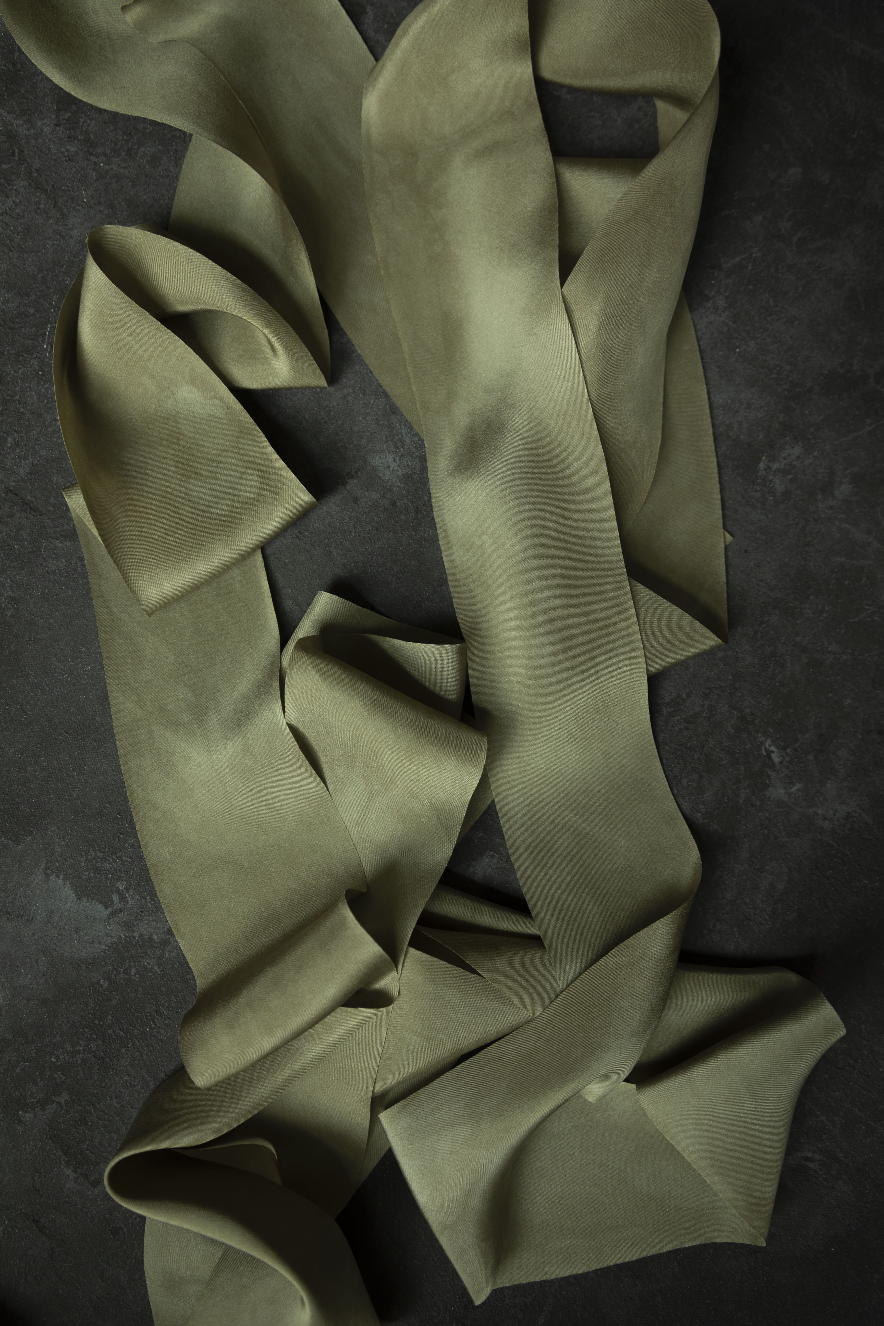 hand dyed green silk ribbon on a dark textured surface