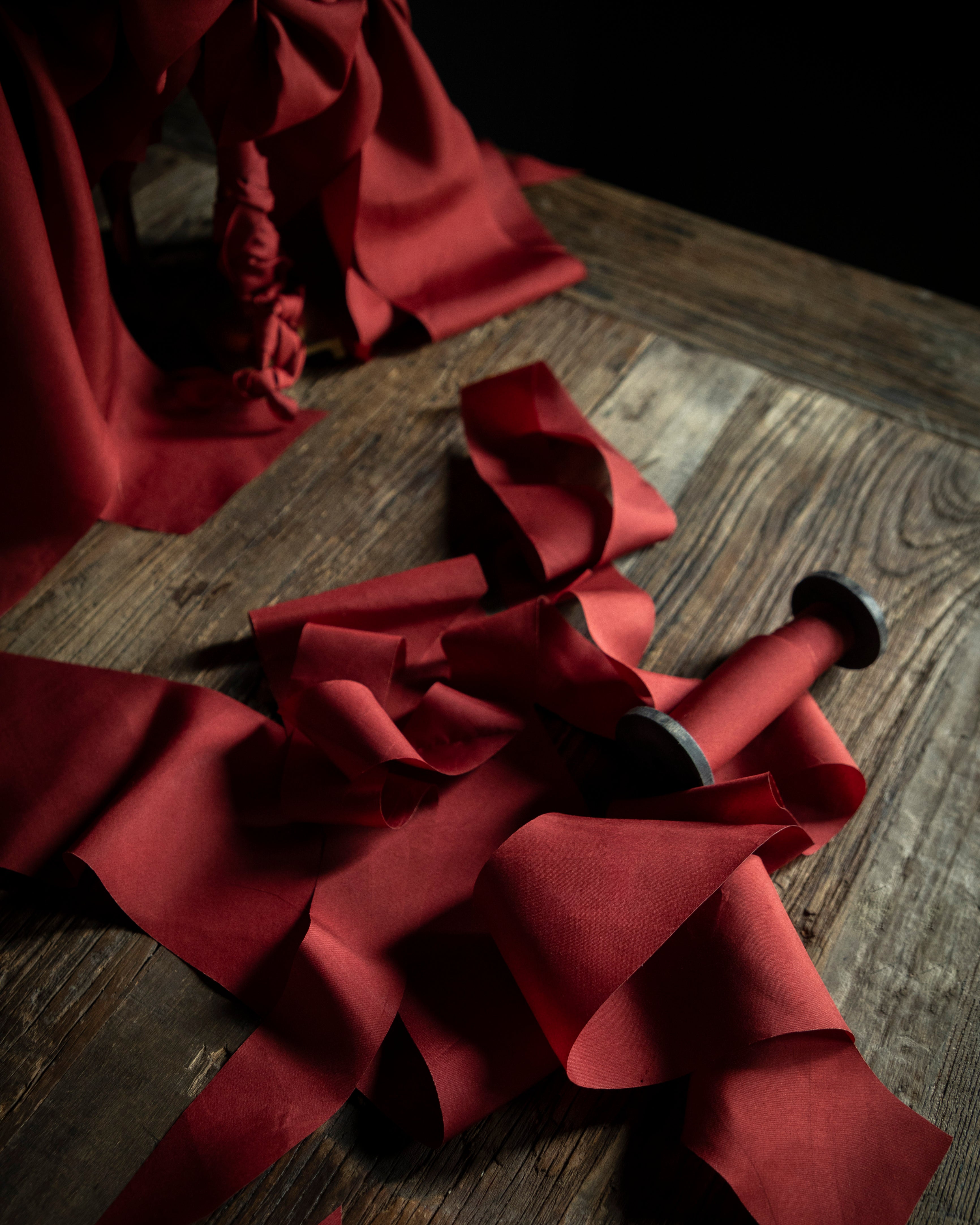 Red silk ribbon with a bow on a wooden surface