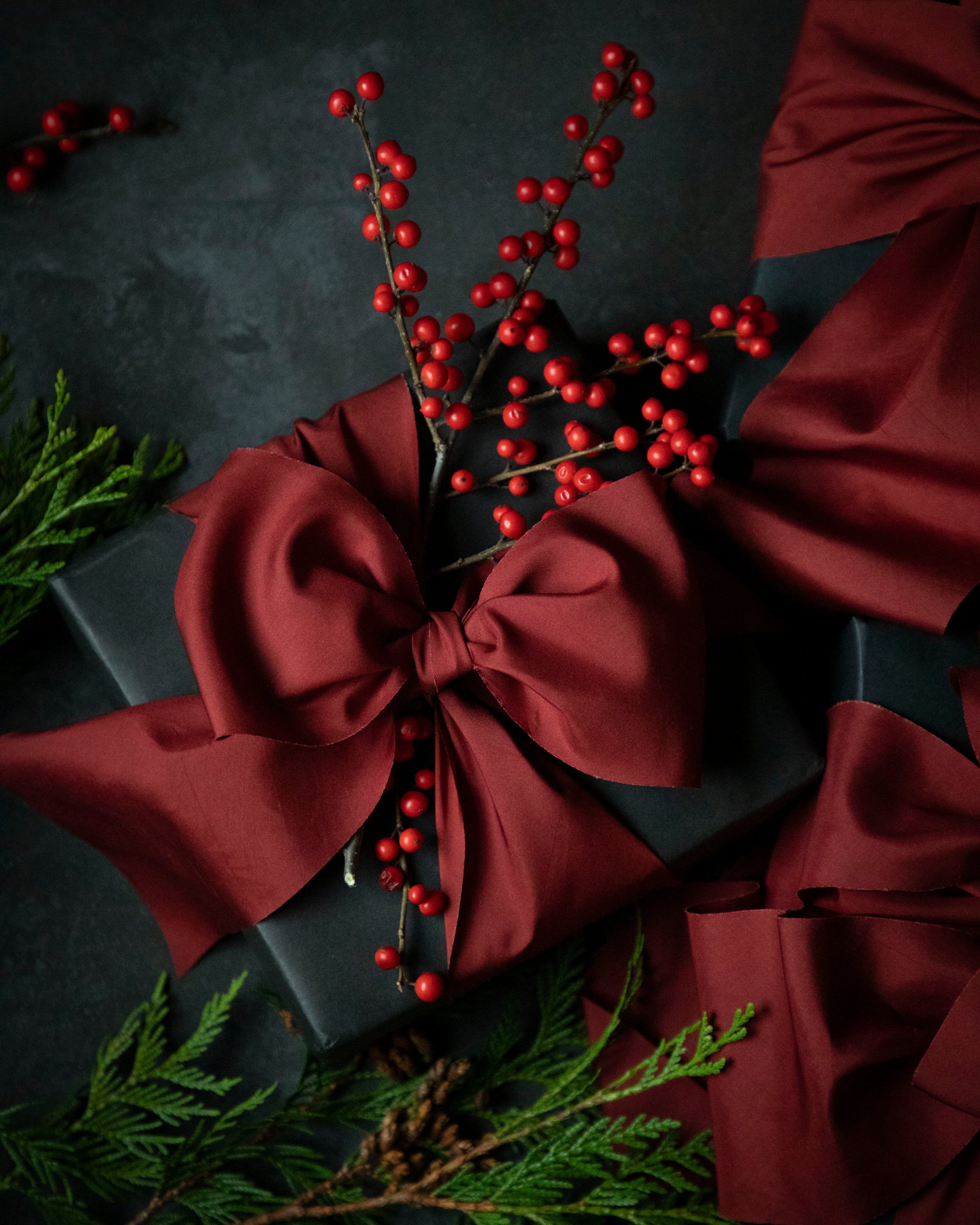 Black gift box with a red ribbon and berries on a dark background