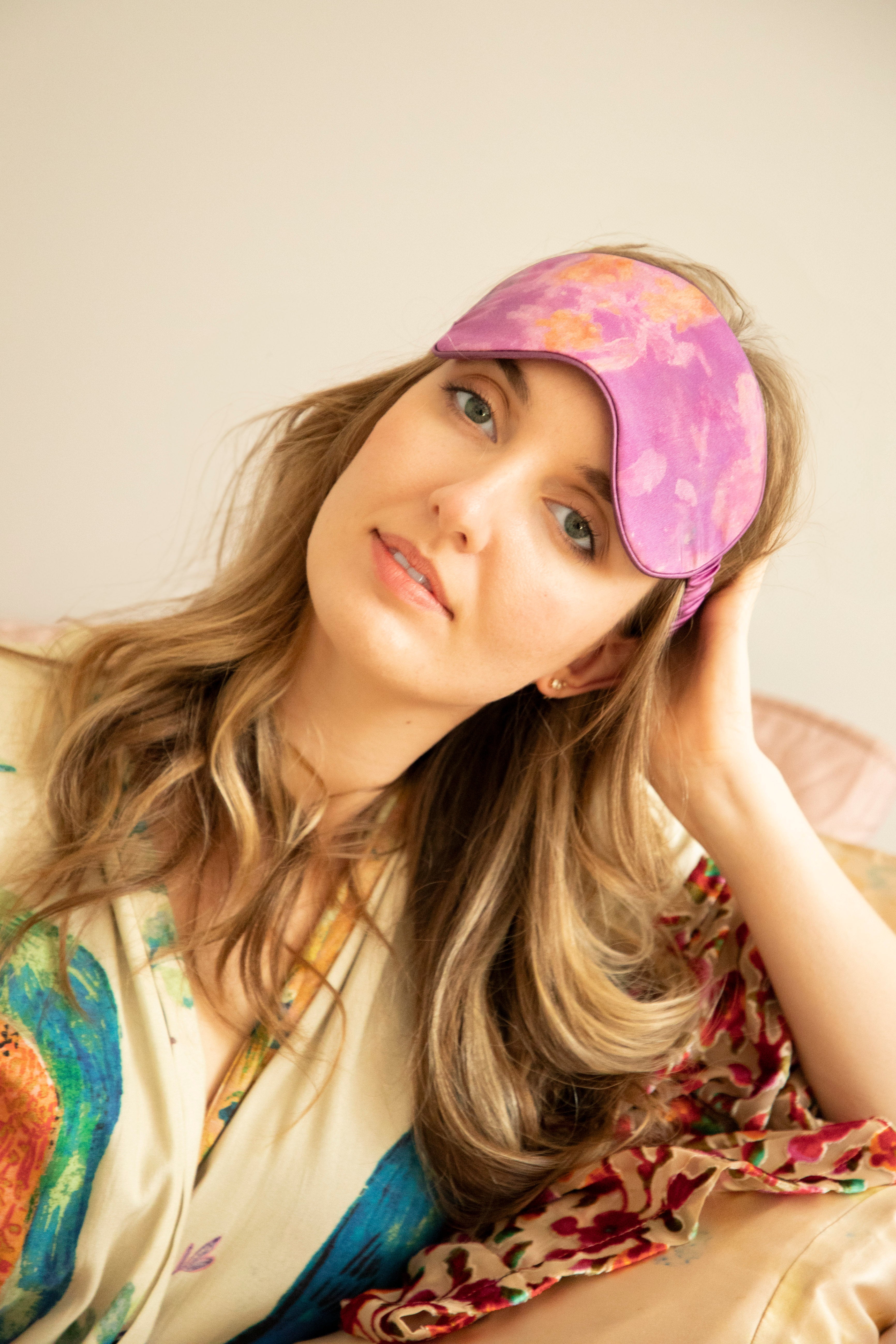 A model wearing a luxurious silk sleep mask adorned with delicate, nature-inspired botanical patterns. The mask exudes a fresh and restorative feel, combining elegance and comfort—a perfect addition to the Anthropologie aesthetic.