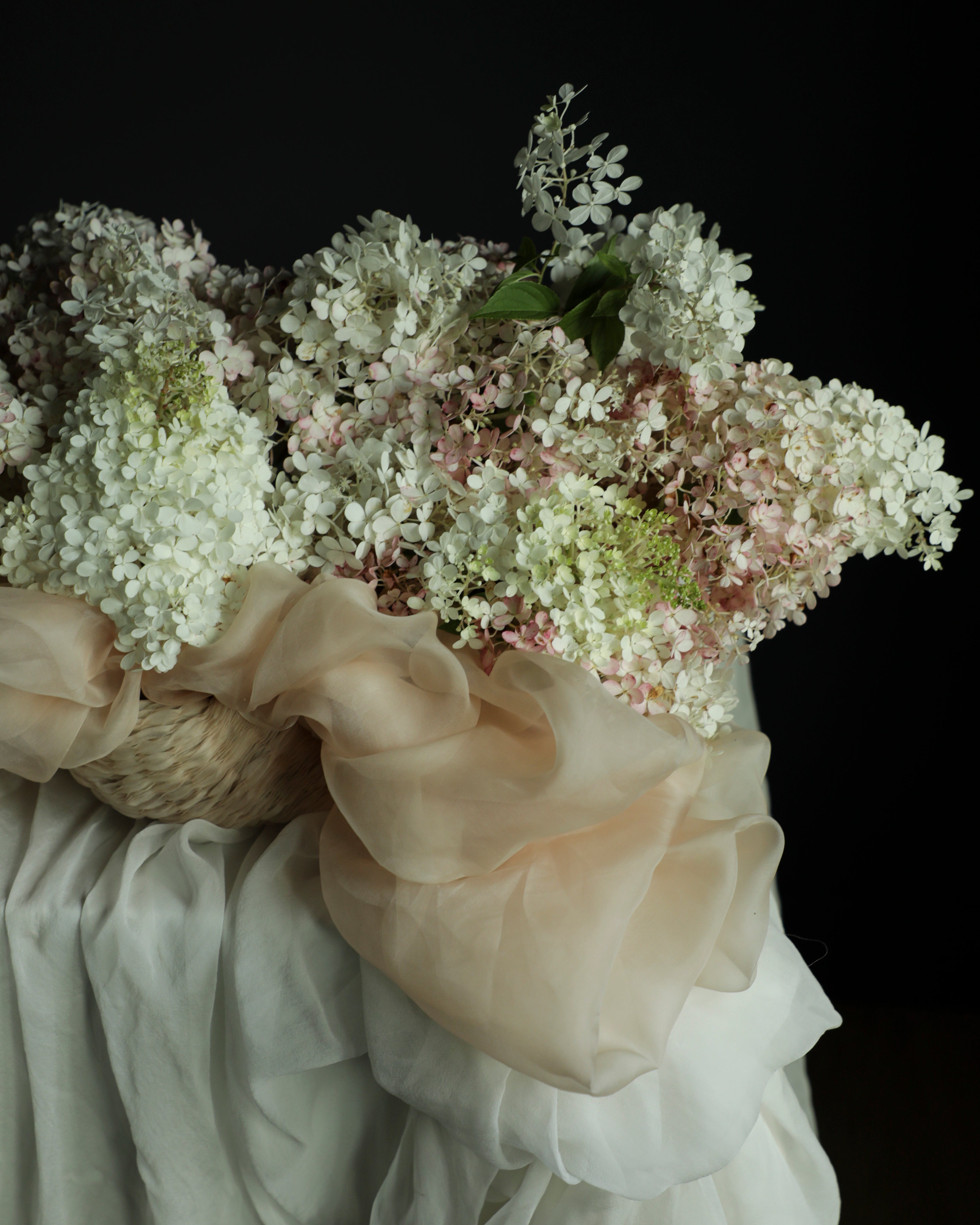 Bouquet of white flowers with ruffled fabric against a dark background