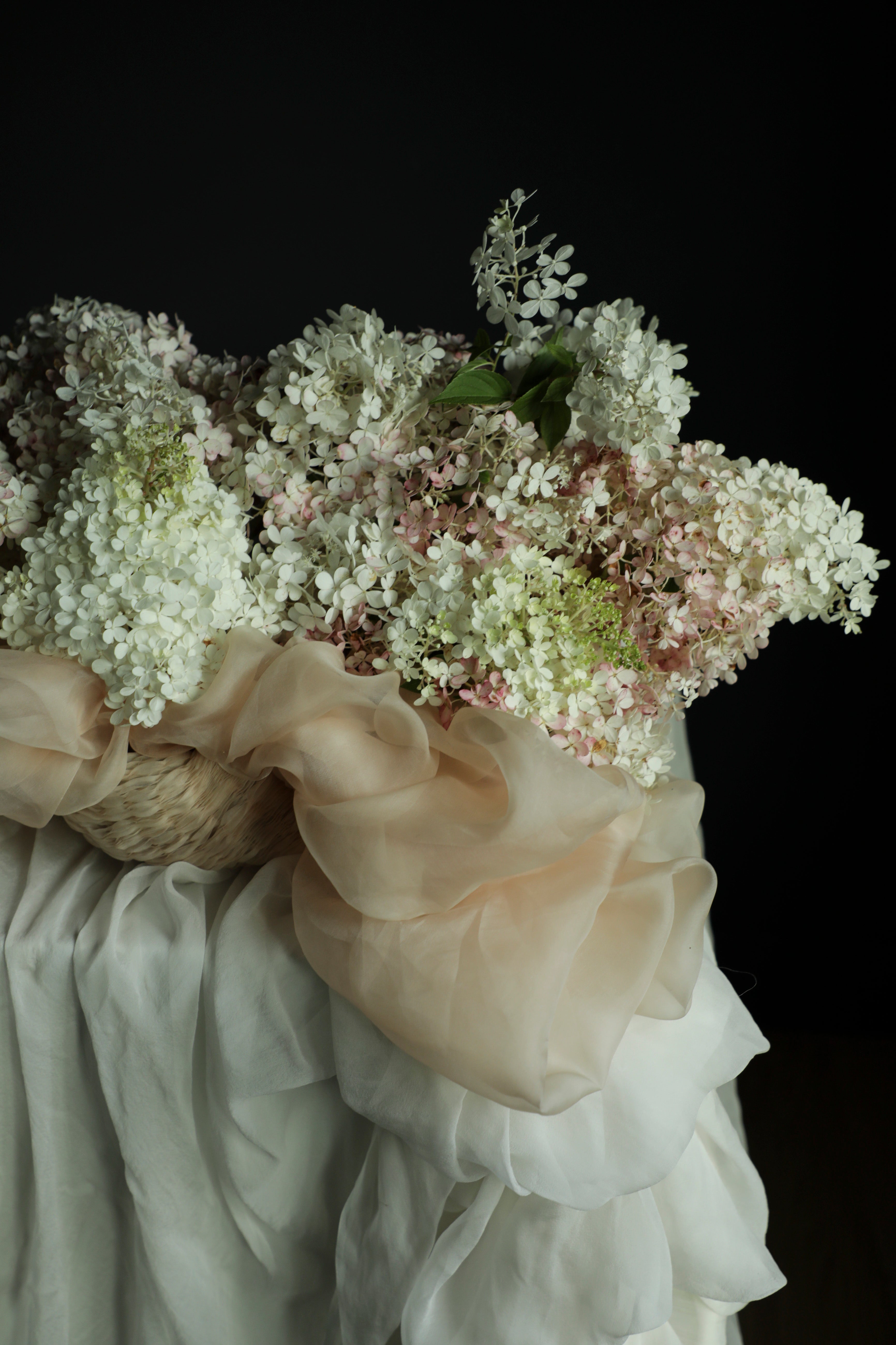 Bouquet of white flowers with ruffled fabric against a dark background