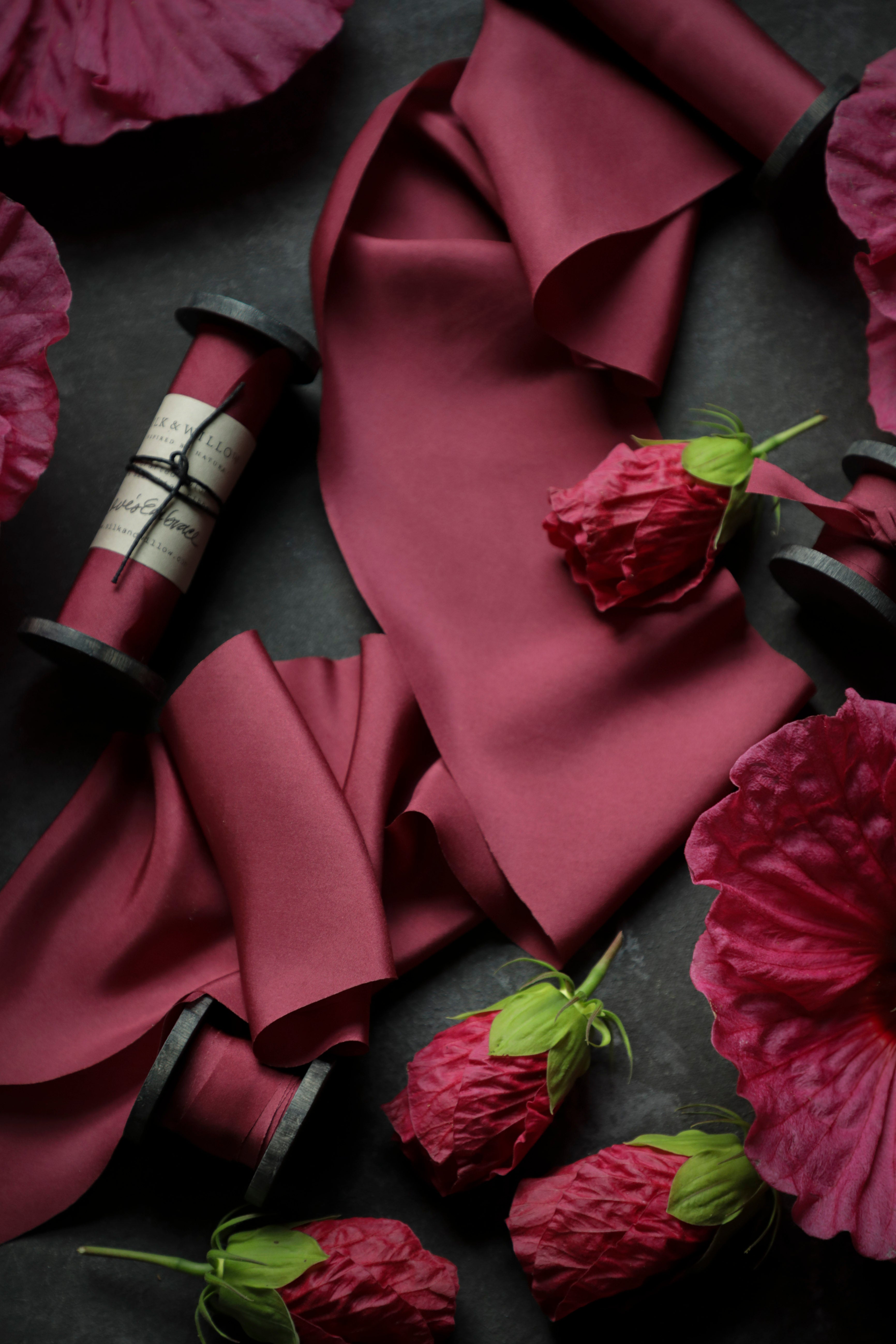 red silk ribbon with pink hibiscus flowers on a dark surface