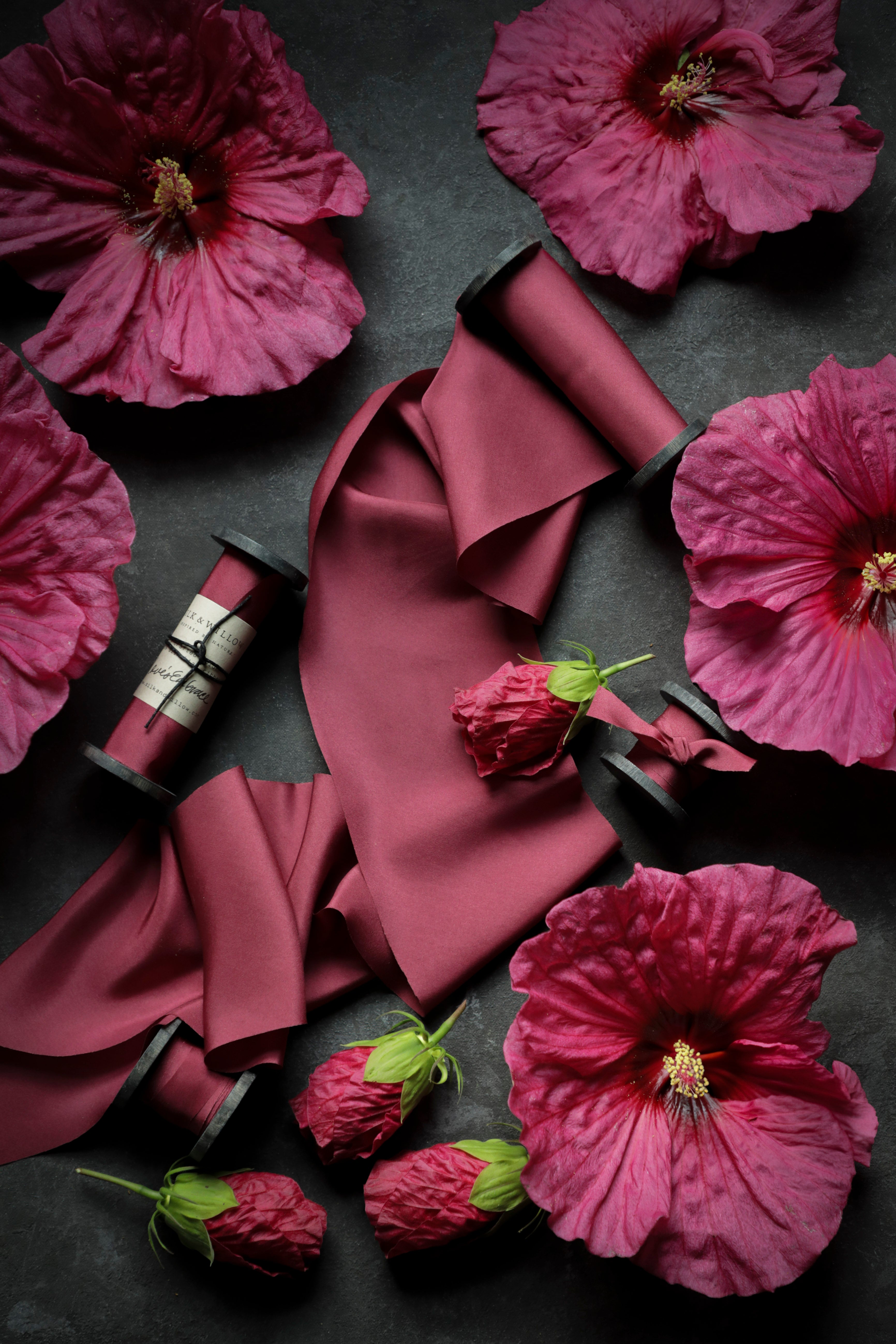 Pink silk ribbon and flowers on a dark surface