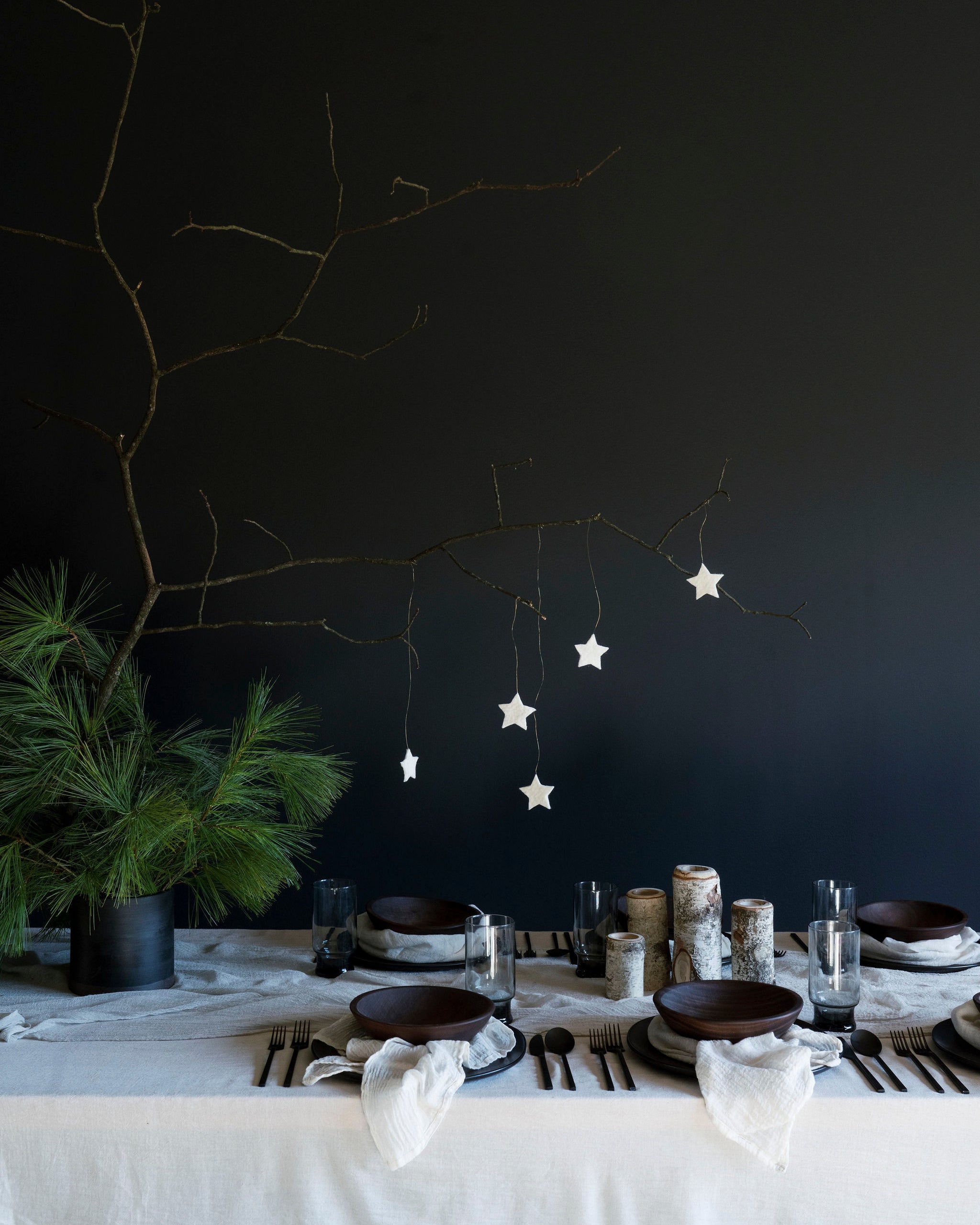 An elegantly set Nordic winter table featuring antique white, plant-dyed, handloomed cotton table runner, showcasing a wabi-sabi, organic design that highlights the heirloom quality of the table linens. Perfect for anyone seeking to create a serene and sophisticated winter tablescape.