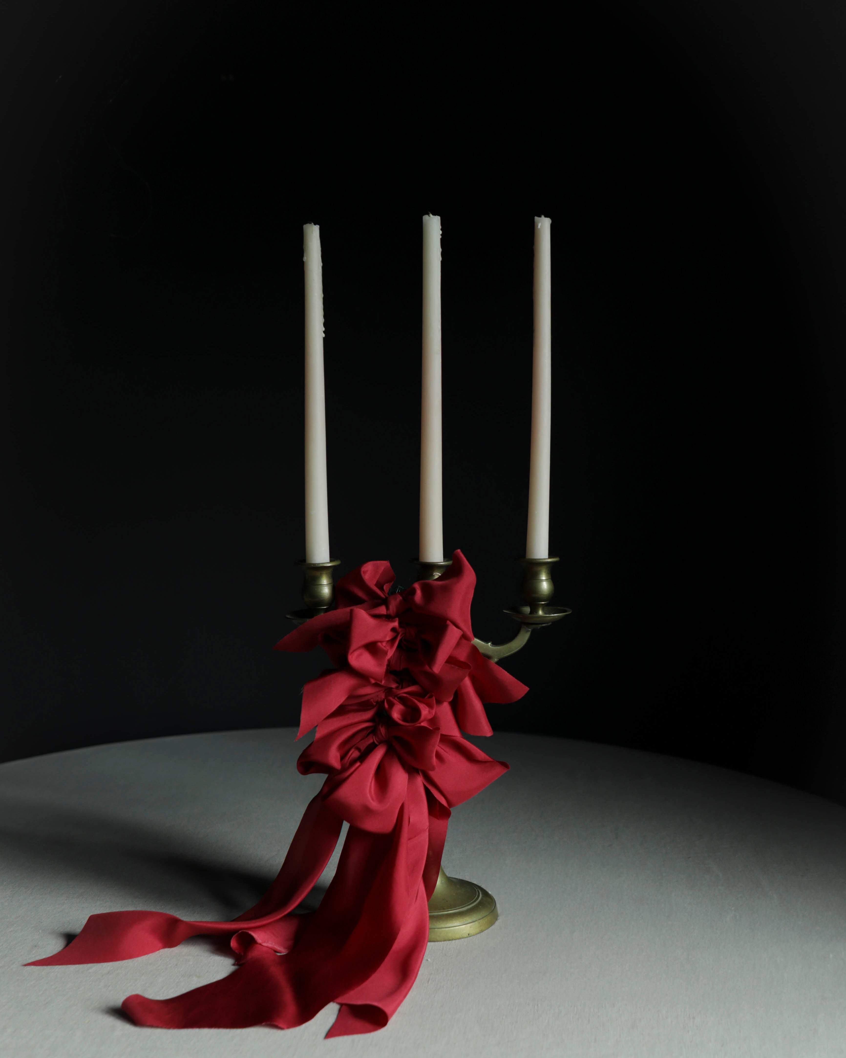 cherry red decor bows on candles against a black wall