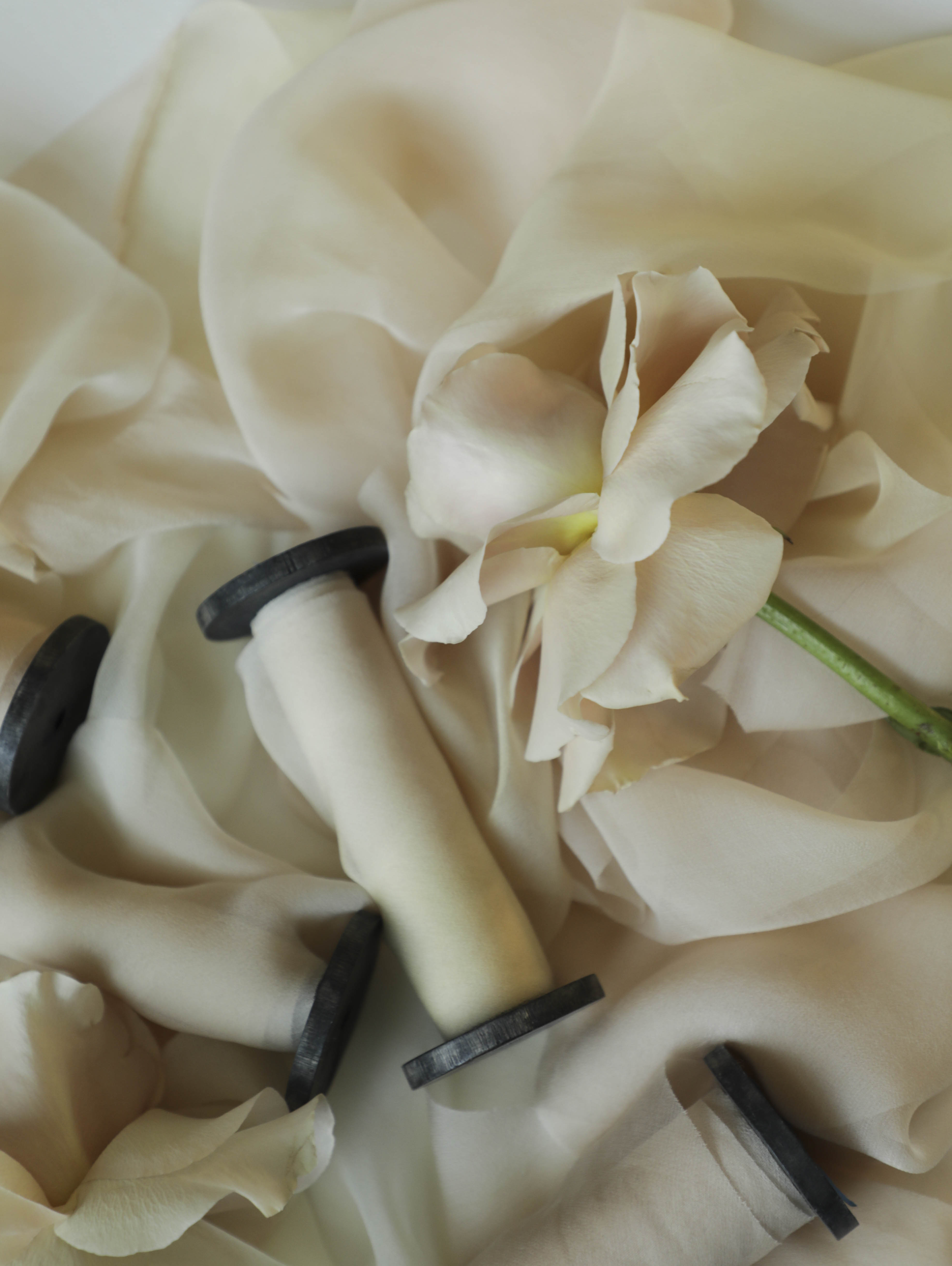 Spool of sheer ribbon on a fabric background with black wood spools