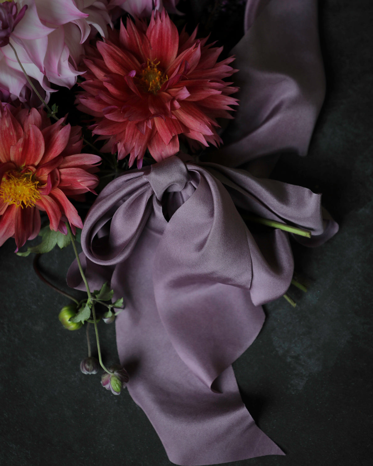 close up od a purple silk ribbon bow tied on the stems of a dahlia bouquet of flowers