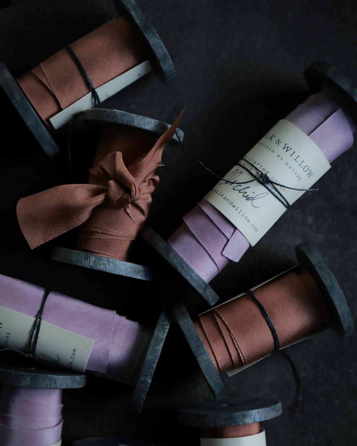 purple and rust colored hand dyed silk ribbons wound on wooden spools