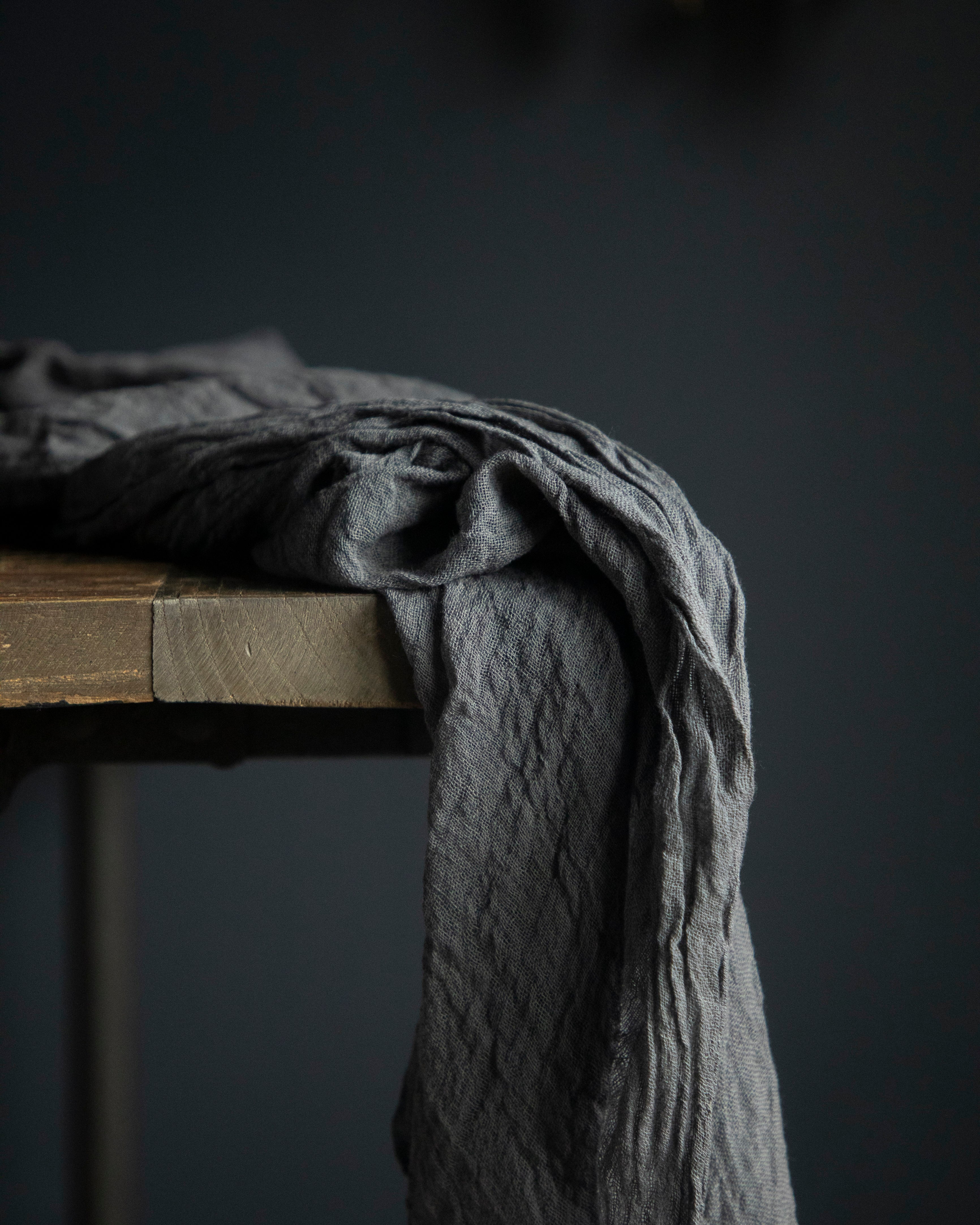 Dark gray fabric draped over a wooden surface against a dark background