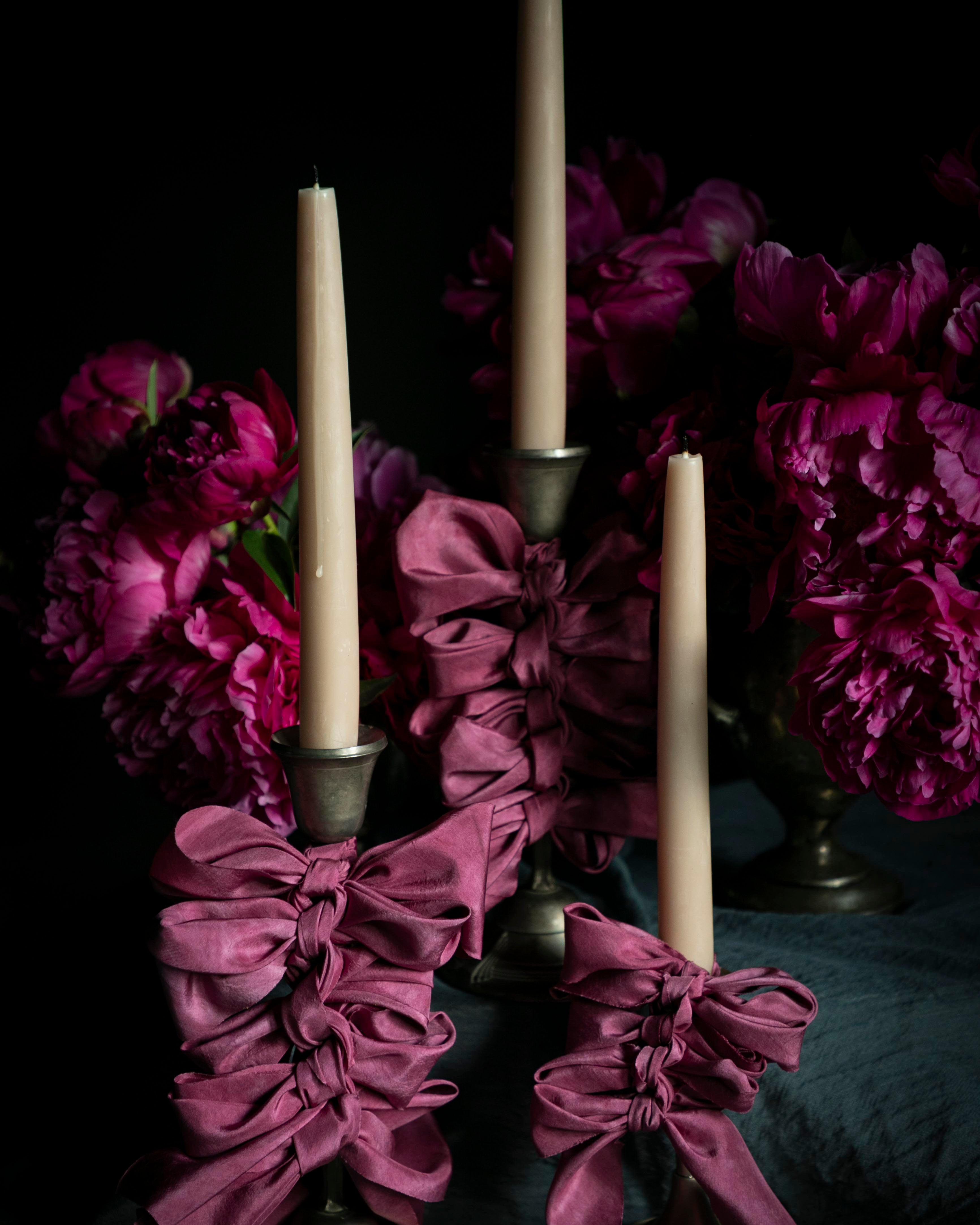 opalite aesthetic. Decorative candle holders with purple ribbons and candles against a dark background