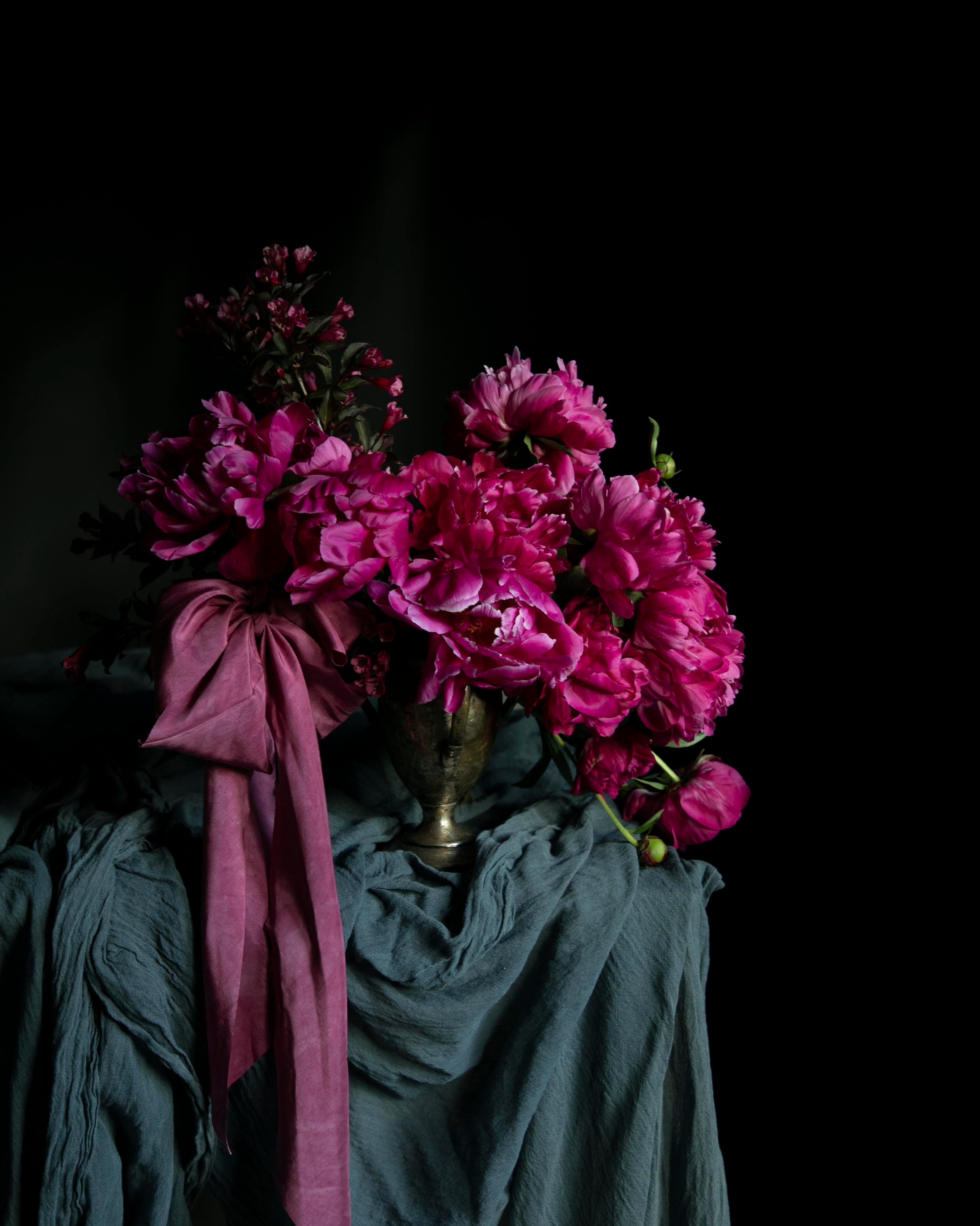 Bouquet of pink flowers with a pink ribbon on a dark background. Unique wedding trends 2027.