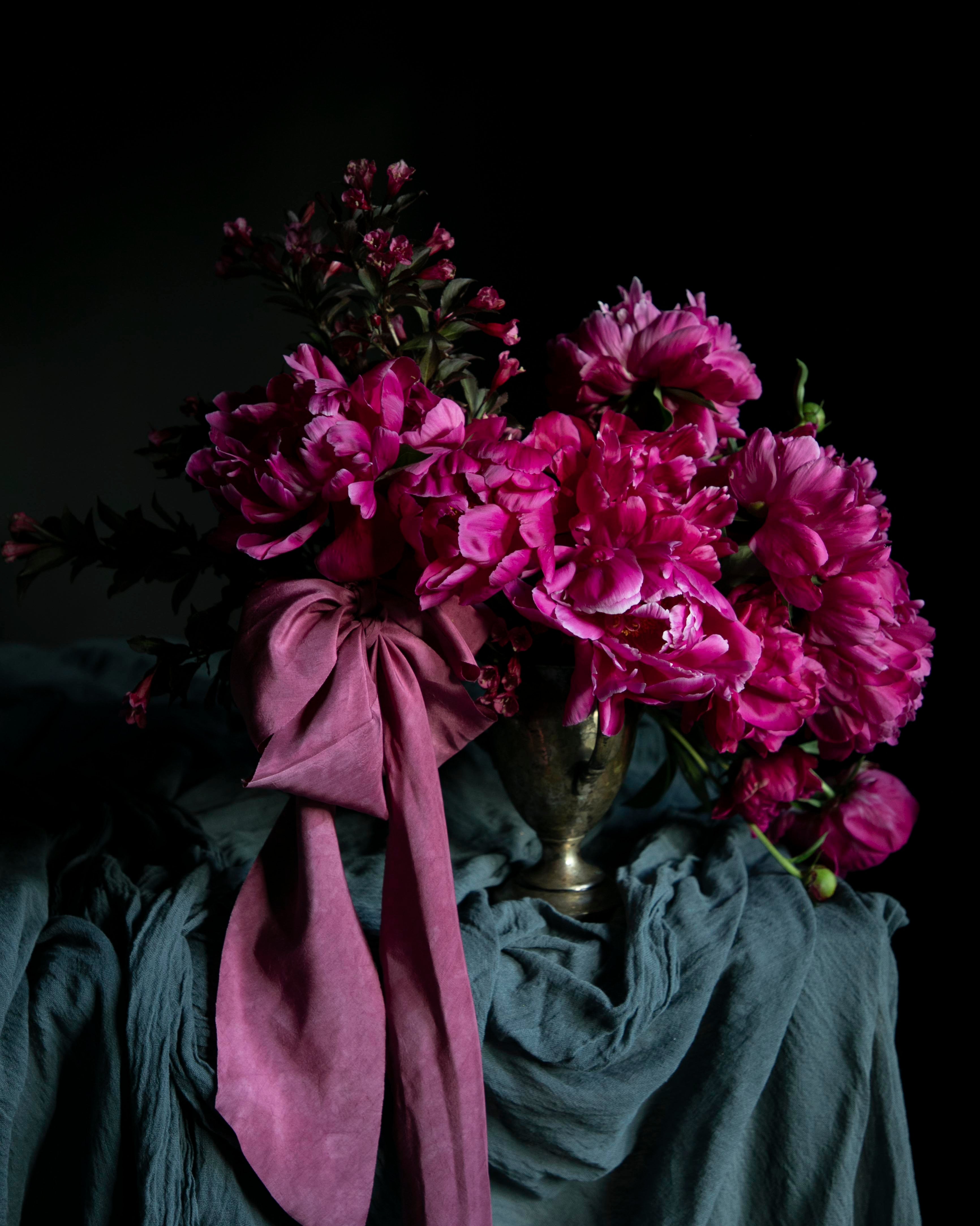 Bouquet of pink flowers with a purple ribbon on a dark background
