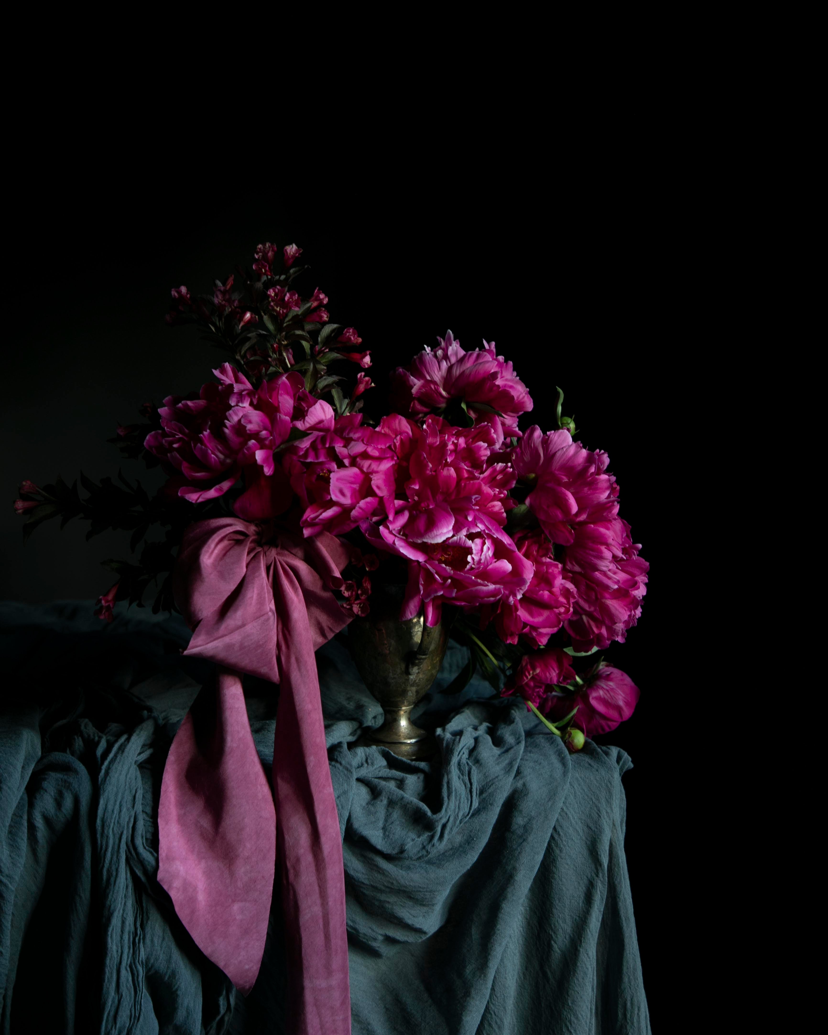 Bouquet of pink flowers with a purple ribbon on a dark background