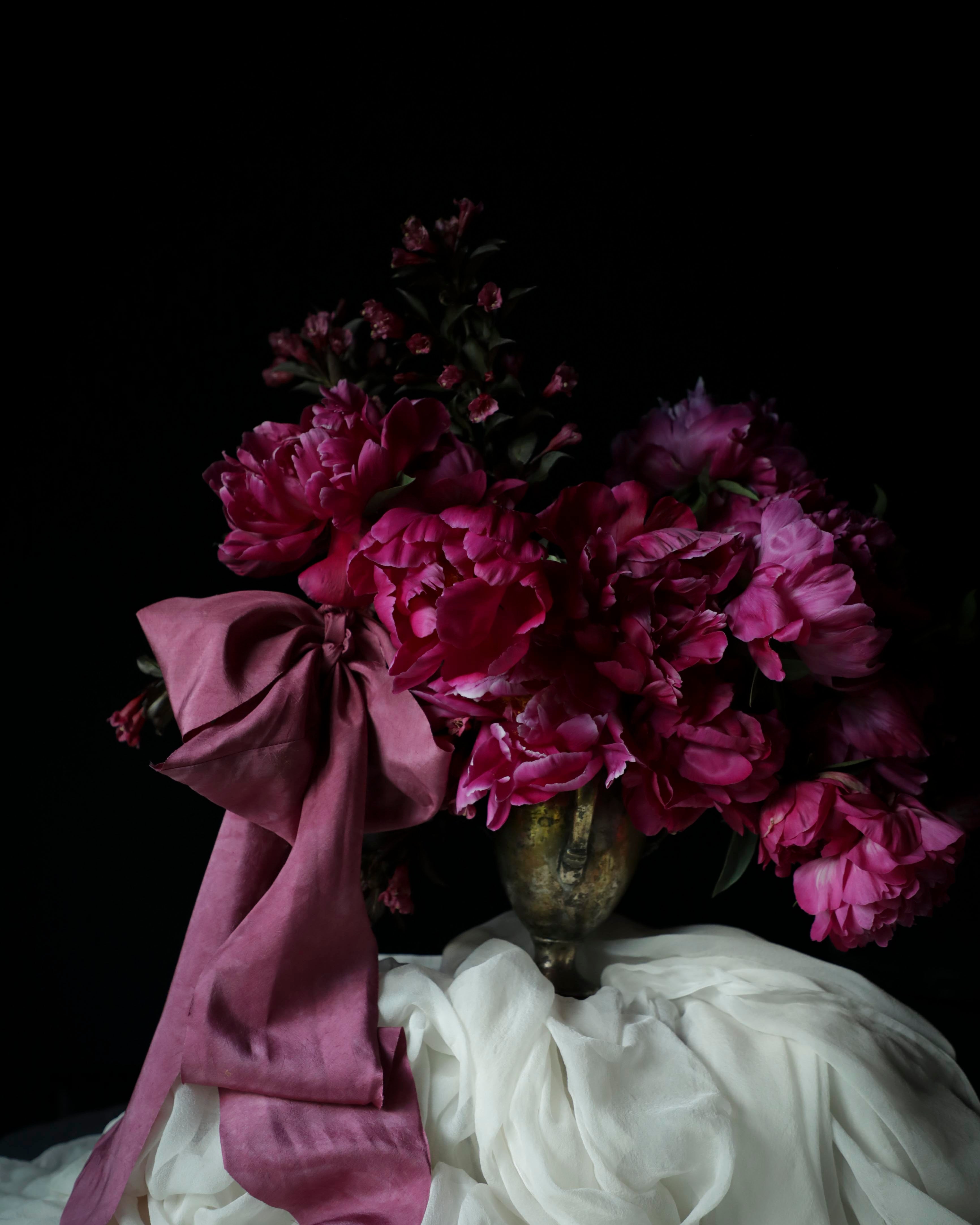 Bouquet of pink flowers with a purple ribbon on a dark background