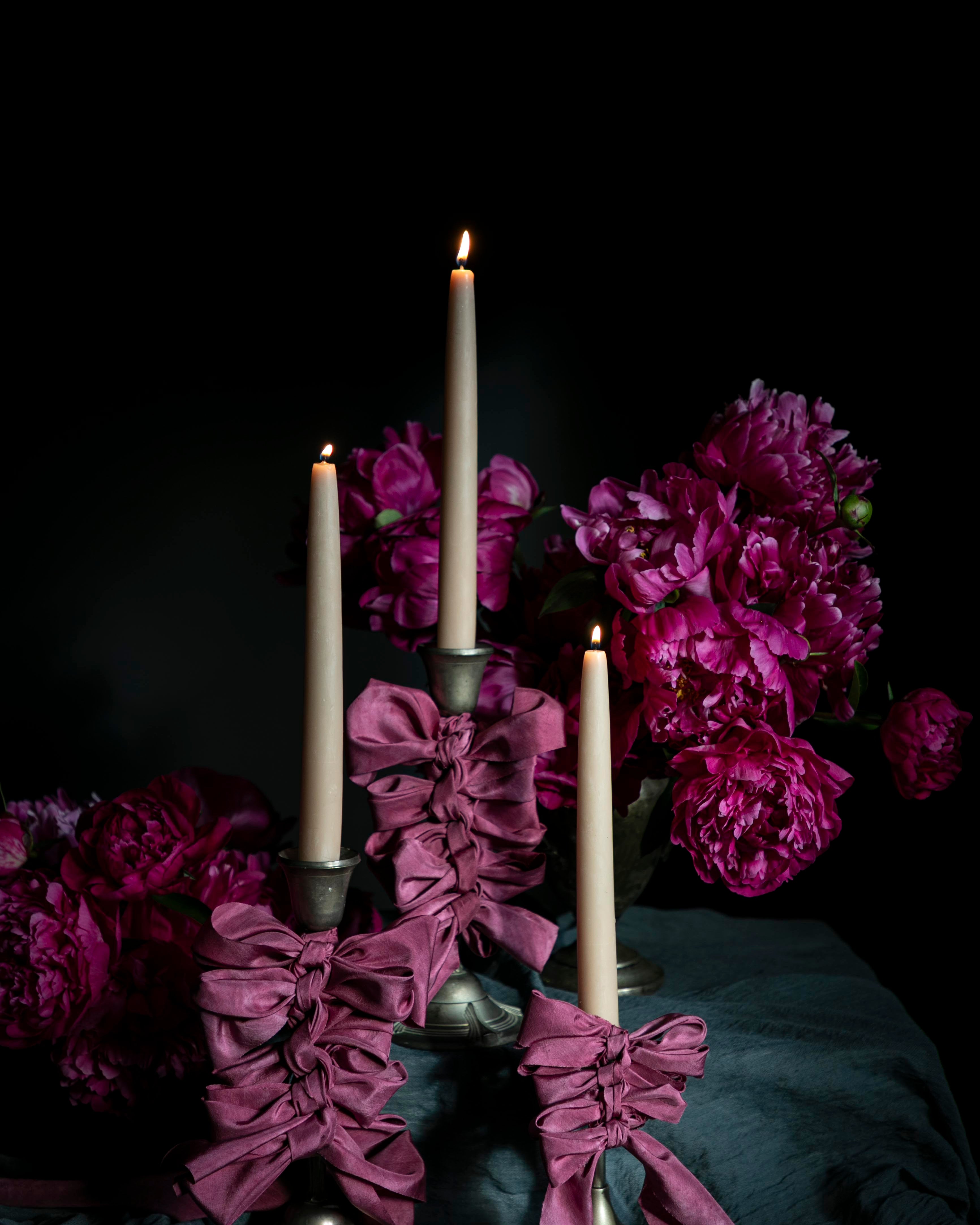 opalite aesthetic. Decorative candle holder with purple-pink ribbons and candles against a dark background.