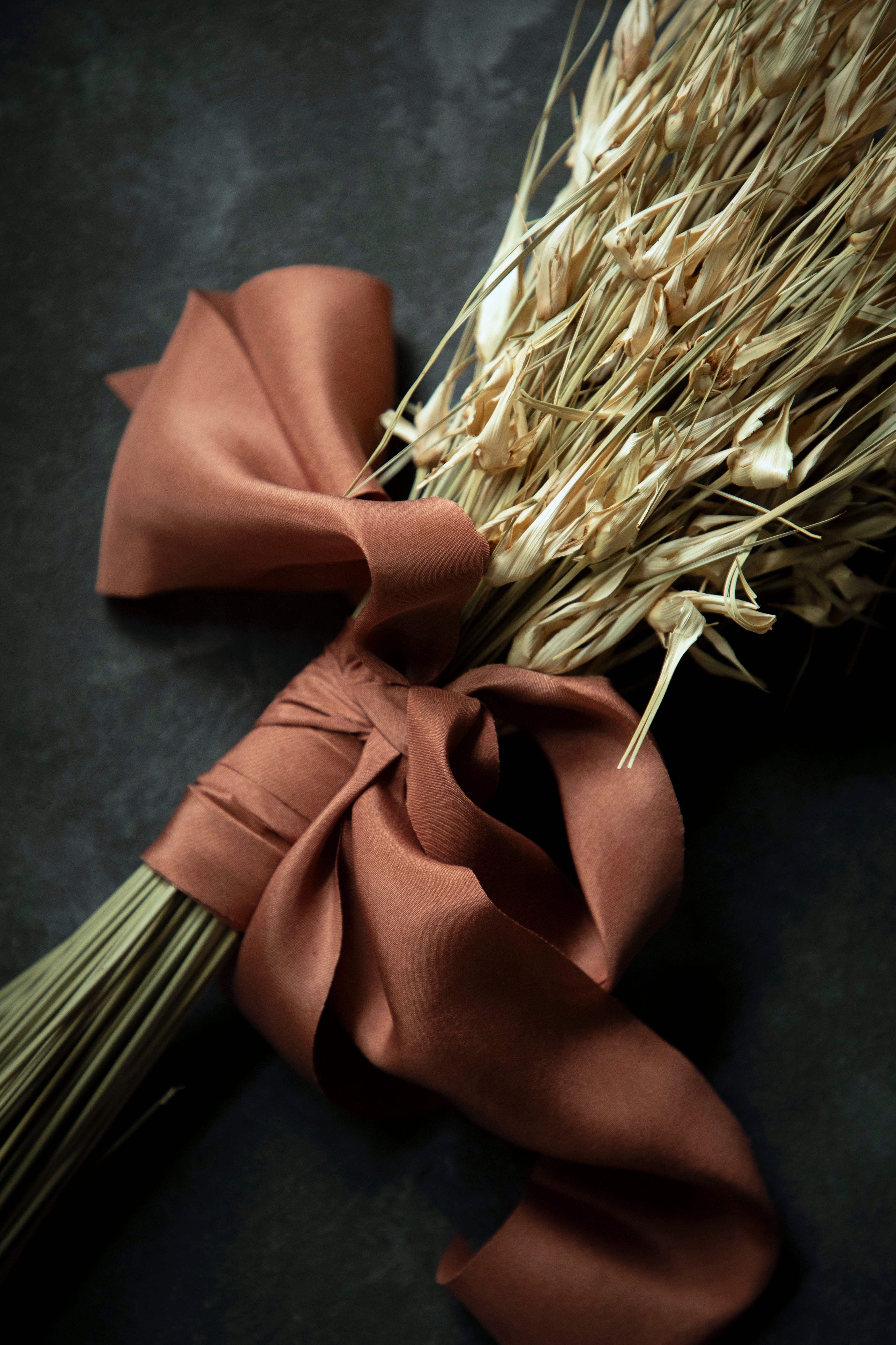Bouquet of dried grasses tied with a copper silk ribbon on a dark surface